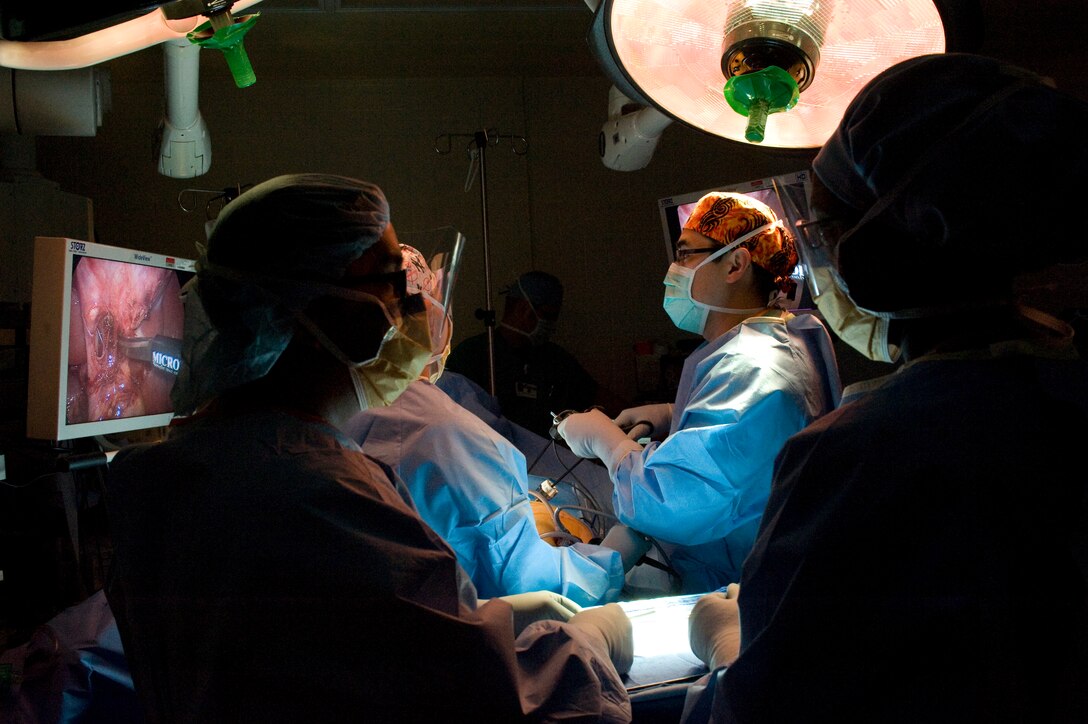Major Michael Matsuura, 779th Surgical Operations Squadron general surgeon, center, accompanied by a surgical team performs laparoscopic surgery on a patient during a gallbladder removal operation April 26. (Photo by Bobby Jones)