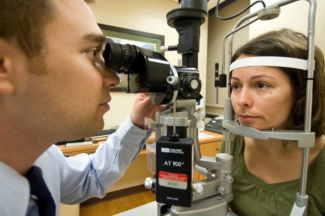 Airman Joseph Metcalf, left, 779th Surgical Operations Squadron ophthalmic technician, performs a slit lamp examination on Angela Craig at the Ophthalmology Clinic April 25. Mrs. Craig is the wife of Army Lt. Col. James Craig, position product director for the program executive office enterprise information system at Fort Belvoir, Va. (Photo by Bobby Jones)