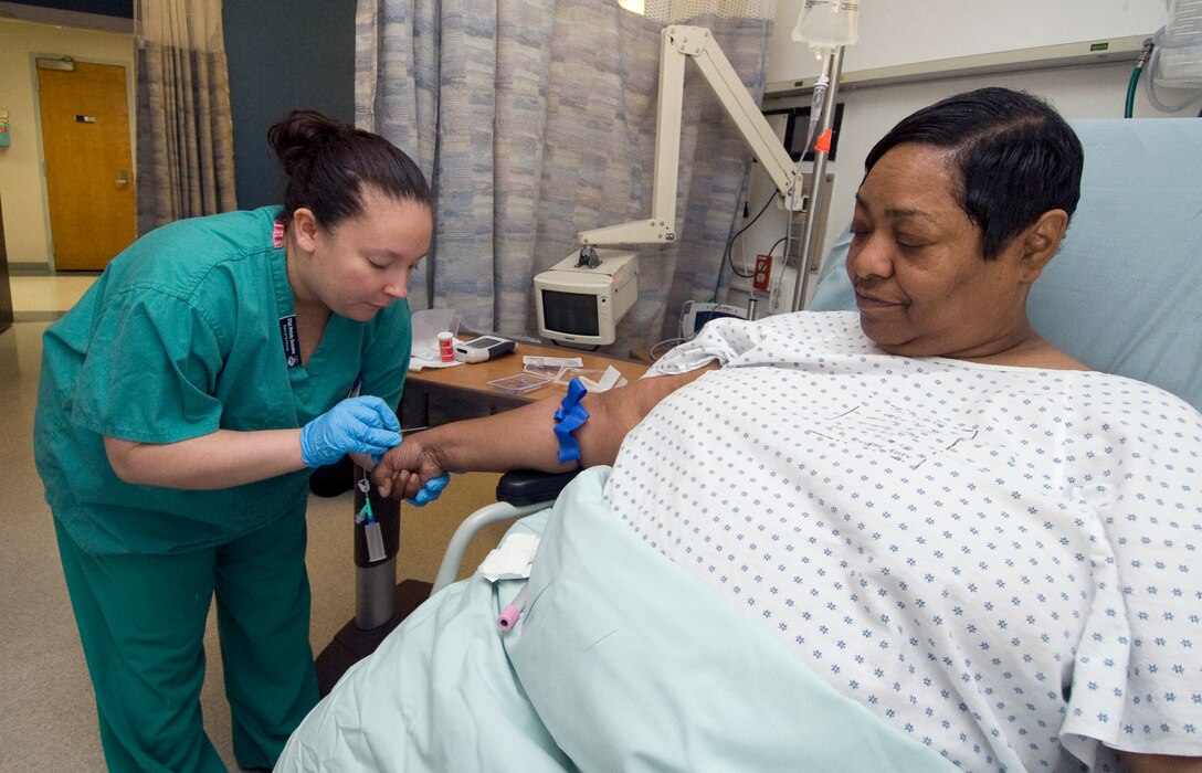 Staff Sgt. Melody Gonzalez, 779th Surgical Operations Squadron medical technician, prepares an intravenous line for Cynthia Little, in the Ambulatory Procedure Unit, prior to her operation April 26. Mrs. Little is the wife of Marine Gunnery Sgt. (Ret.) Rufus Little. (Photo by Bobby Jones)