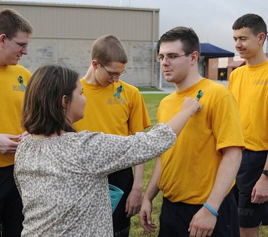 Joint Base Charleston - Weapons Station Sexual Assault Response Coordinator Tiffany Minaudo-Mizzell places a teal ribbon on Machinist's Mate Fireman Will Rinehart's shirt during a base-wide race-for-the-cause event held in conjunction with Sexual Assault Awareness Month at JB CHS - W.S., April 27. The event, hosted by the Sexual Assault Prevention and Response program and Weapons Station athletic Department, provided more than 100 participants with a teal ribbon to pin on their shirts, signifying their personal pledge to never commit, condone or remain silent about sexual violence against men, women or children. MMFN Rinehart, originally from Bixby Okla., is attached to Navy Nuclear Power Training Command at JB CHS - WS. (U.S. Navy photo/Mass Communication Specialist 1st Class Jennifer Hudson)