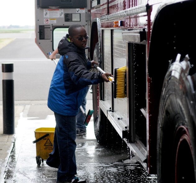 RAF MILDENHALL, England -- Ajani Tonge, son of Tech. Sgt. Latisha Cole, scrubs an RAF Mildenhall fire truck during an RAF Mildenhall Youth Center community service project April 26, 2011, at the fire department. This project is part of the youth center?s monthly community involvement project. The purpose of the community involvement project is to get youth involved with the local community and to see different types of jobs on base. (U.S. Air Force photo/Airman 1st Class Rachel Waller)