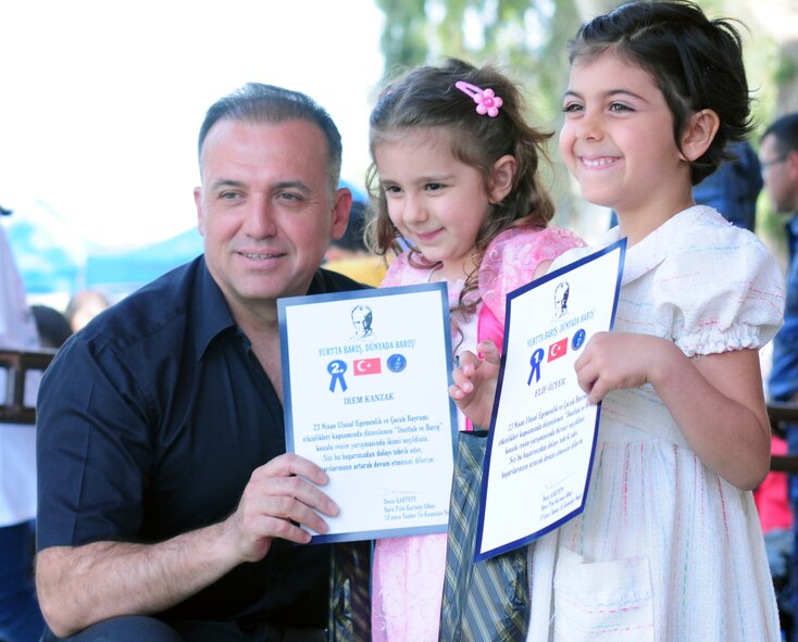 Col. Deniz Kartepe, the commander of the 10th Tanker Command, presents certificates to Irem Kanzak and ElIf Ozyer for their 2nd and 1st place finishes respectively in an art and poetry contest for National Sovereignty and Children?s Day. Colonel Kartepe presented the awards during a Children?s Day festival April 17, 2011, at Incirlik Air Base, Turkey. The event was hosted by the Turkish air force 10th Tanker Command and was open to all Incirlik personnel. The event offered an opportunity for camaraderie and partnership-building for all Incirlik personnel, and was a chance to celebrate both Turkish children on their national holiday and military children during the Month of the Military Child, officials said.  (U.S. Air Force photo by 1st Lt. Gina McKeen/Released)