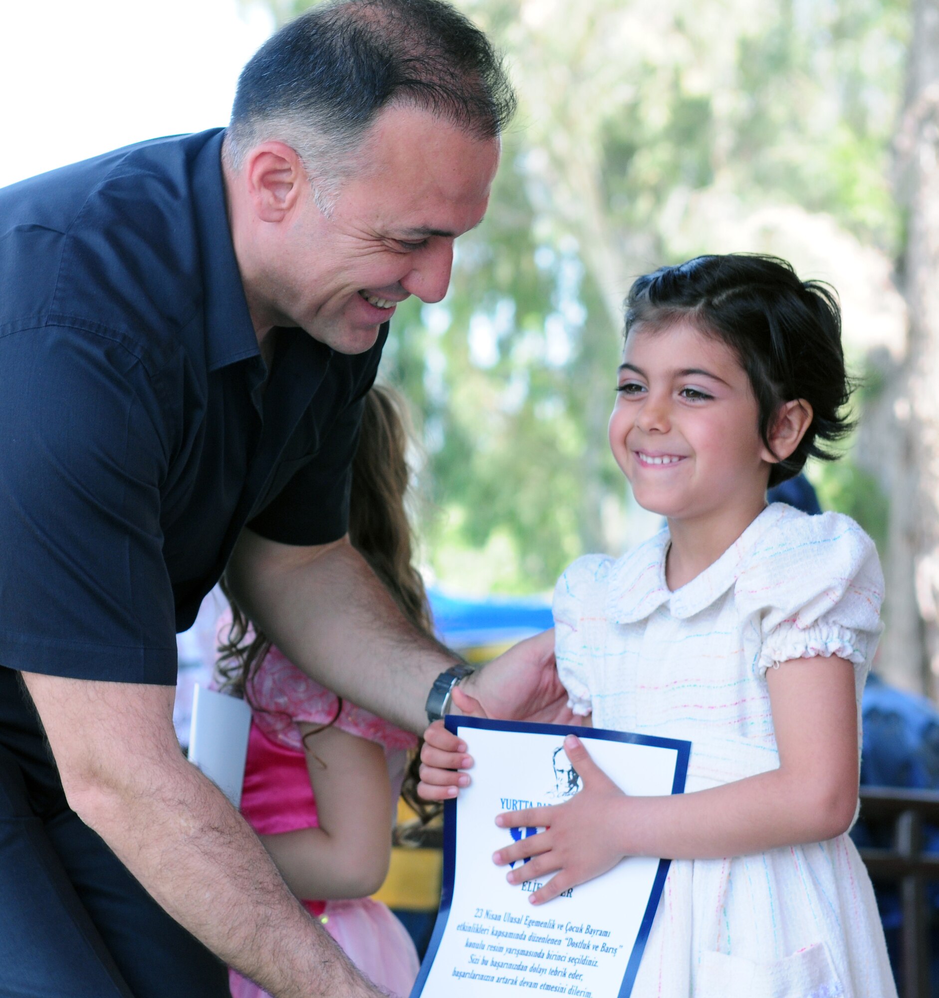 Col. Deniz Kartepe, the commander of the 10th Tanker Command, presents a certificate to ElIf Ozyer for her artwork, which won 1st place in the age 5 and 6 division of the National Sovereignty and Children?s Day Art and Poetry contest. Colonel Kartepe presented the award during a Children?s Day festival April 17, 2011, at Incirlik Air Base, Turkey. The event was hosted by the Turkish air force 10th Tanker Command and was open to all Incirlik personnel. The event offered an opportunity for camaraderie and partnership-building for all personnel here, and was a chance to celebrate both Turkish children on their national holiday and military children during the Month of the Military Child, officials said.  (U.S. Air Force photo by 1st Lt. Gina McKeen/Released)