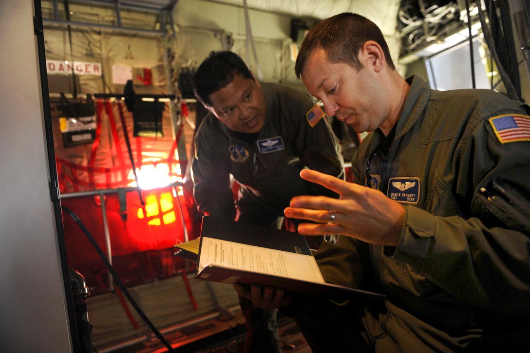 U.S. Air Force Tech. Sgt. Marc Garnsey and Senior Master Sgt. Vergel De Dios conduct preflight checks on the Modular Airborne Firefighting System in a C-130J Hercules aircraft on Dyess Air Force Base, Texas, April 26, 2011. Garnsey and De Dios are assigned to the 115th Airlift Squadron, California Air National Guard.