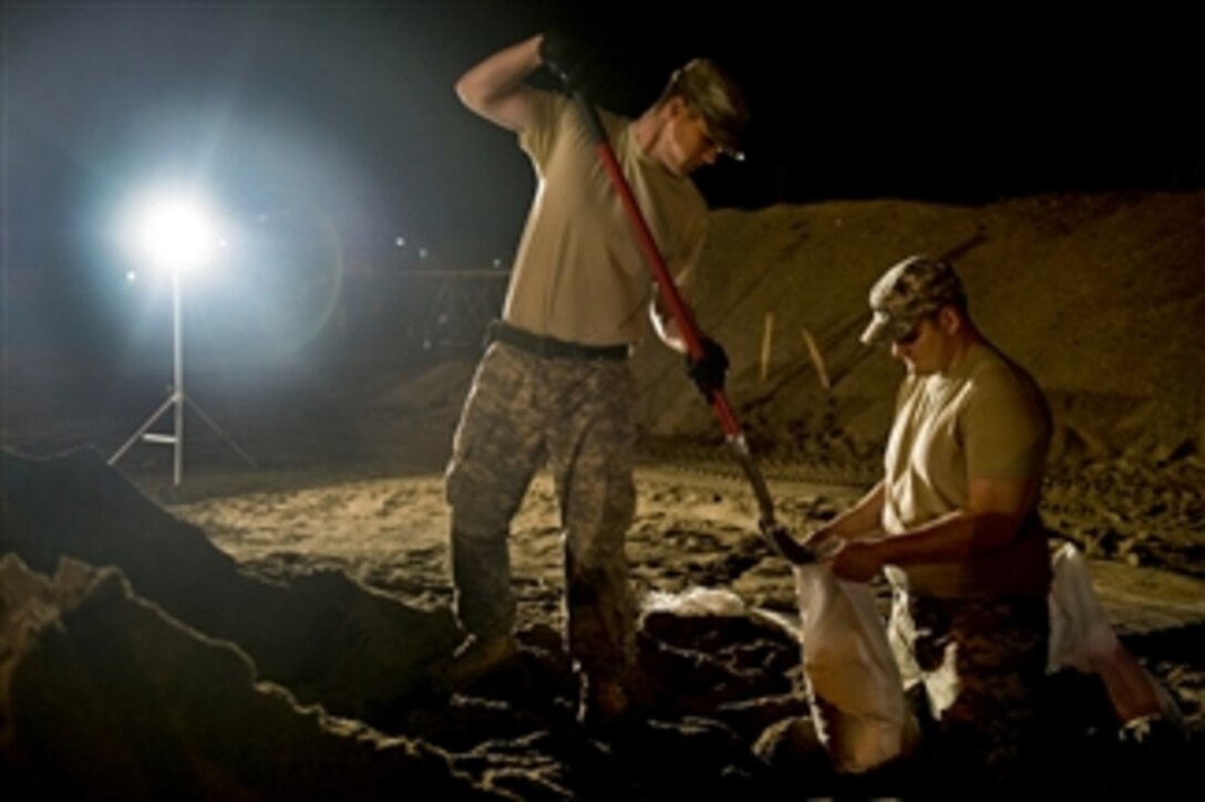 U.S. Army Spc. Benjamin Sukys and Spc. Robert Thorp work through the night filling sandbags at the Indiana Department of Transportation branch in Vincennes, Ind., on April 26, 2011.  Sukys and Thorp, both in the Indiana National Guard, are assigned to Company B, 1st Battalion, 151st Infantry Regiment.  The soldiers alternated working six-hour shifts around the clock to fill an order of 100,000 sandbags.  