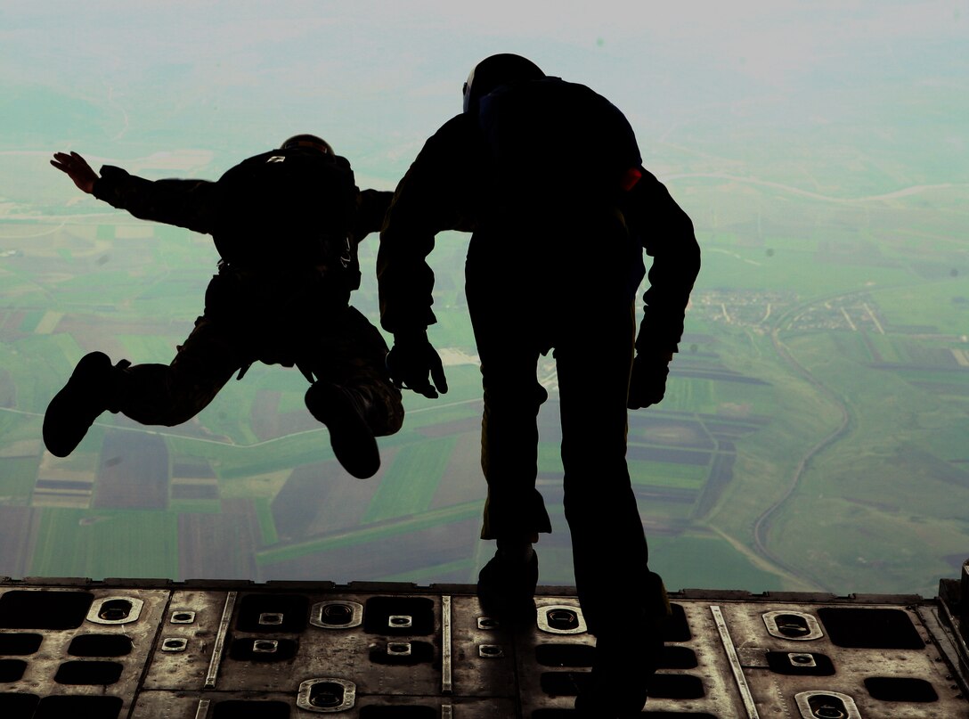 While flying at an 10,000 feet, two Romanian paratroopers fling themselves off a KC-130 Hercules and into the open air toward the patched landscape below while conducting a High-Altitude, Low-Opening (HALO) combat jump as part of parachute operations with Black Sea Rotational Force 11. U.S. Marine and Romanian jumpmasters conducted combat jump operations at Camp Turzii recently, about 260 miles north of Mihail Kogalniceanu, to share experience and give Romanian troops the opportunity to jump from a KC-130.