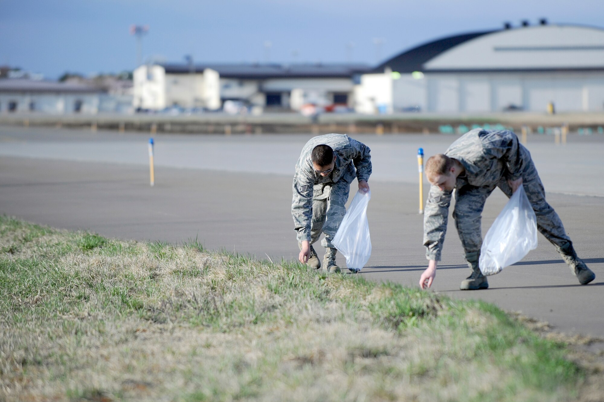 MISAWA AIR BASE, Japan -- Staff Sgt. Vang Le, left, and Senior Airman Kevin Shoultz, 35th Maintenance Squadron, pick up foreign object damage on the airfield April 29. An estimated 140 pounds of foreign objects, trash and debris were collected off the airfield. (U.S. Air Force photo/Staff Sgt. Marie Brown/Released)
