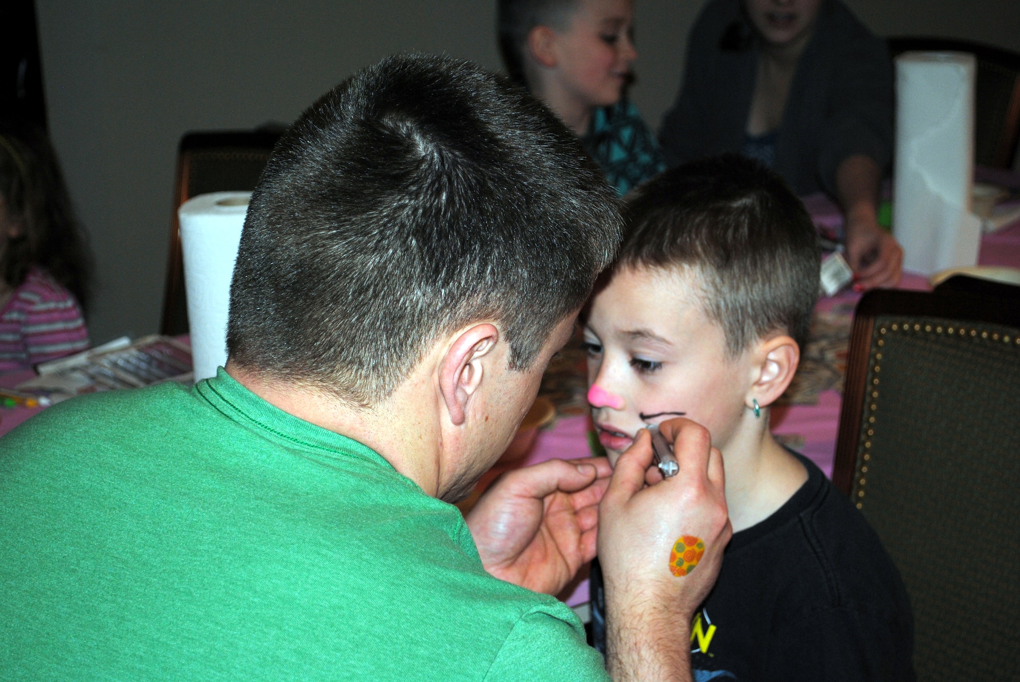 Tyler Clark, 8, gets his face painted like the Easter bunny by volunteer David Lietz.  (U.S. Air Force photo/Airman Cortney Hansen)
