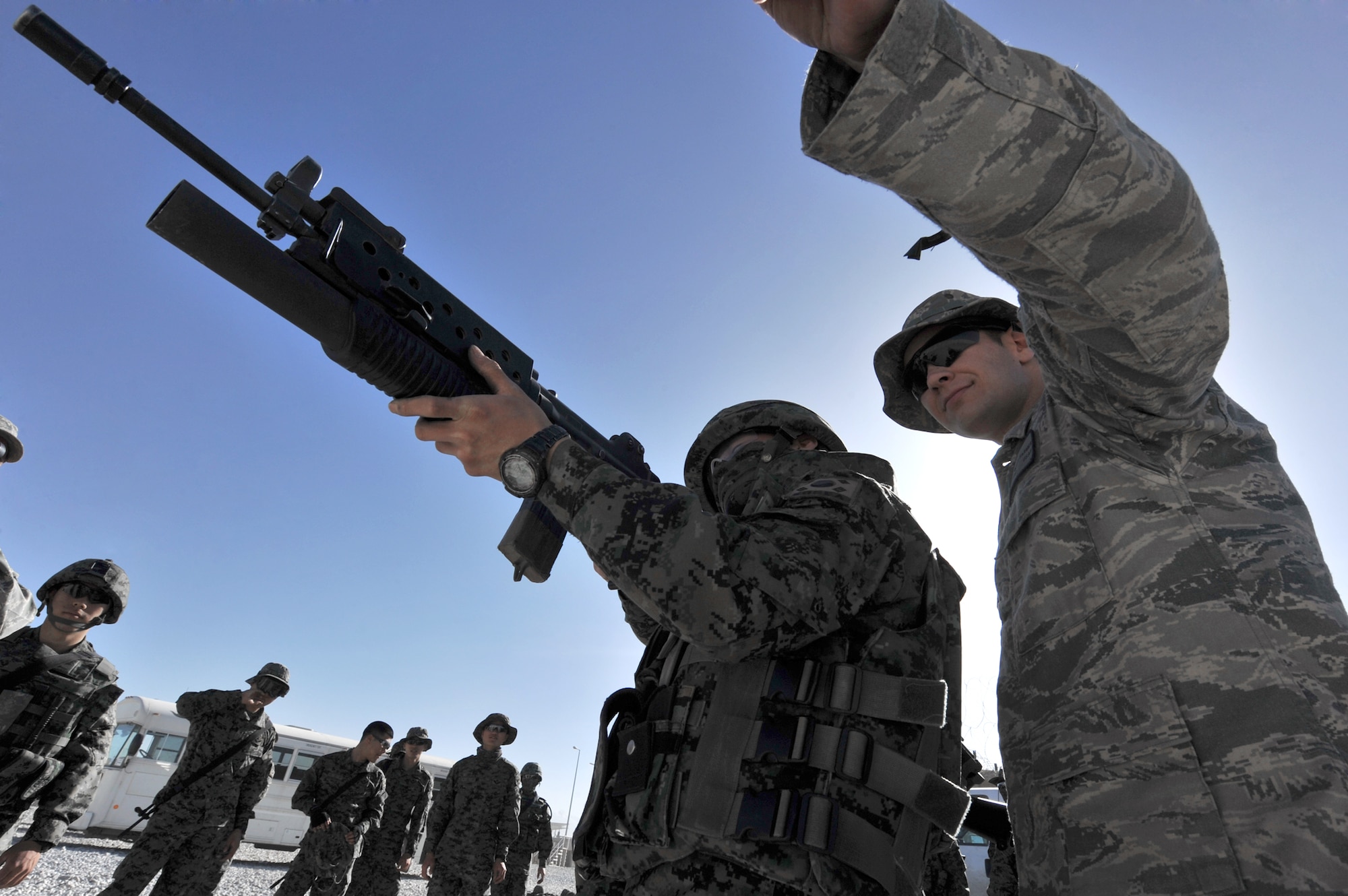 Senior Airman Gary Farmer, of the 455th Expeditionary Security Forces Squadron, watches Staff Sgt. Jon Myung Jae, a South Korean security forces soldier, fire a non-lethal 40 mm sponge round during M203 grenade launcher training at Bagram Airfield, Afghanistan, April 22, 2011. Members from the South Korean army security force have to qualify on a M203 grenade launcher before joining Bagram's base defense. (U.S. Air Force photo/Senior Airman Sheila Devera)