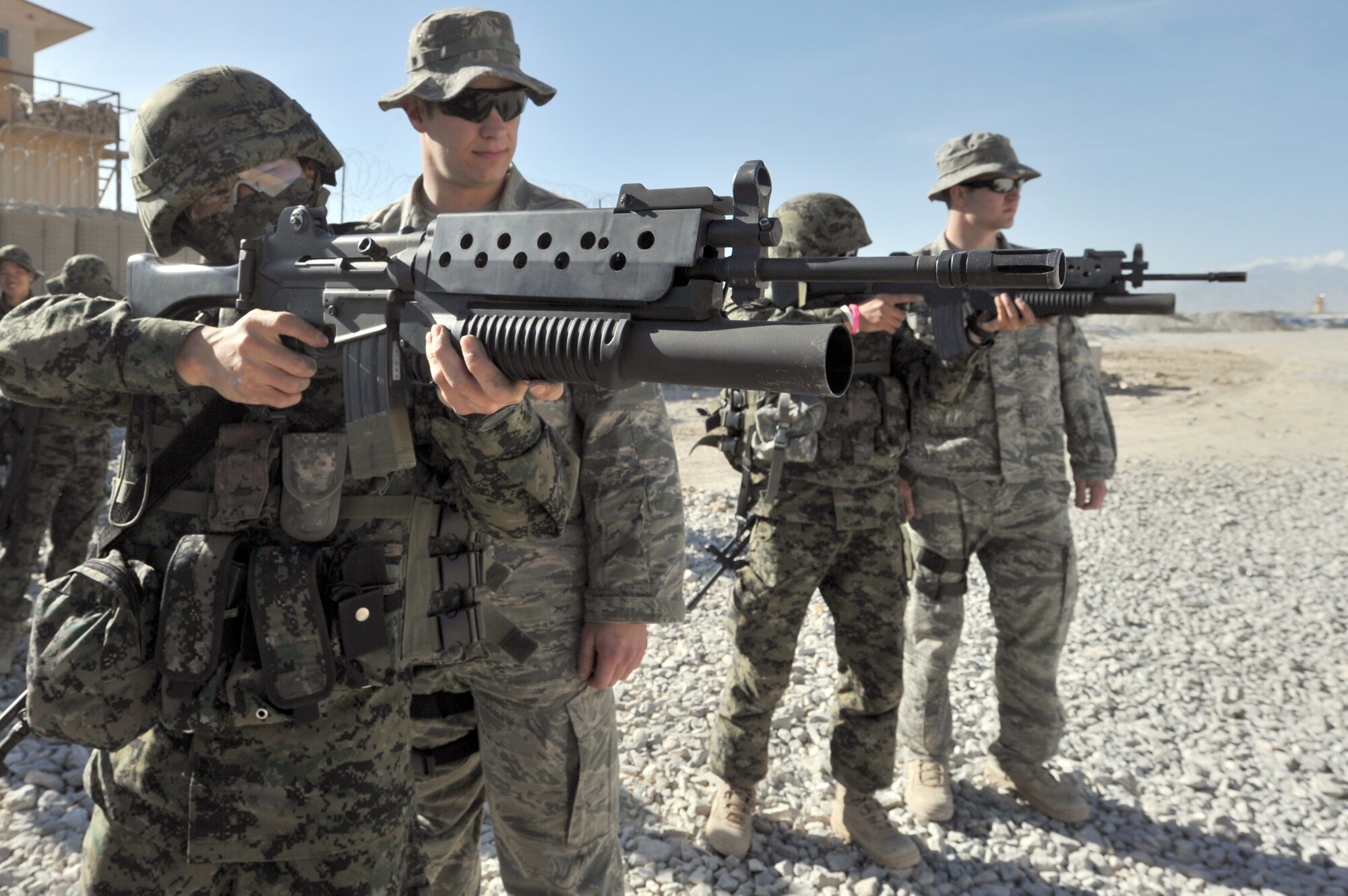 Senior Airman Gary Farmer (second from left) and Staff Sgt. Mason Flores, both from the 455th Expeditionary Security Forces Squadron, watch Staff Sgt. Jon Myung Jae (left) and Staff Sgt. Kim Tae Young, both South Korea security force soldiers, fire non-lethal 40 mm sponge rounds during M203 grenade launcher training at Bagram Airfield, Afghanistan, April 22, 2011. (U.S. Air Force photo/Senior Airman Sheila deVera)
