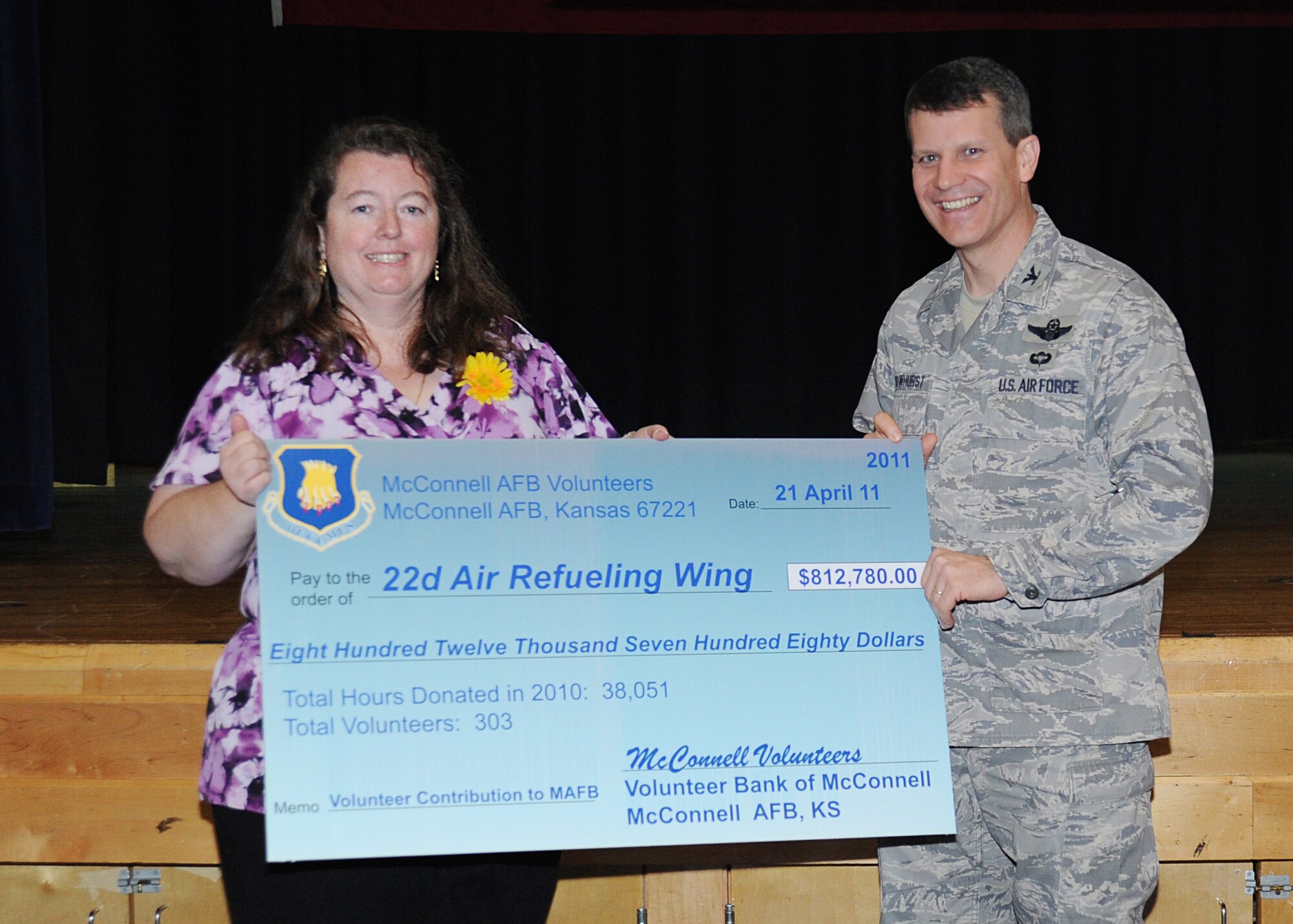 Madeleine Goodner, McConnell volunteer, presents Col. Jamie Crowhurst, 22nd Air Refueling Wing commander, with a $812,780 check, representing the money the base saved because of volunteer efforts during 2010 April 21, 2011, McConnell Air Force Base, Kan. The check was presented during the 2011 Volunteer Appreciation Ceremony. Team McConnell members worked more than 38,000 volunteer service hours in 2010. (U.S. Air Force Photo/Airman 1st Class Katrina M. Brisbin)