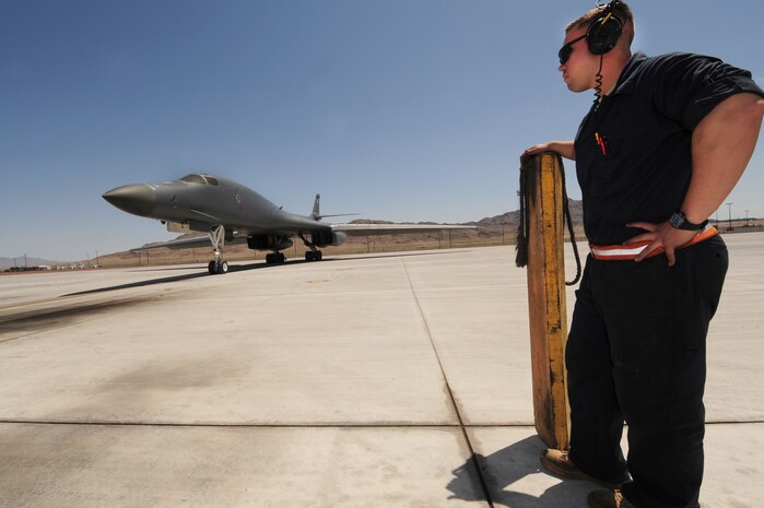 NELLIS AIR FORCE BASE, Nev. -- Airman 1st Class Joseph Dowdell, a crew chief from the 28th Aircraft Maintenance Squadron, Ellsworth Air Force Base, S.D., stands with a chock as a B-1 Lancer comes in from a mission during Green Flag West 11-6, April 25.  Green Flag West replicates irregular warfare conditions currently found in Southwest Asia. Aircrews, work closely with Air Force joint terminal attack controllers. Pilots train for a missions such as close air support, and aerial reconnaissance.  (U.S. Air Force photo by Staff Sgt. William P.Coleman)  