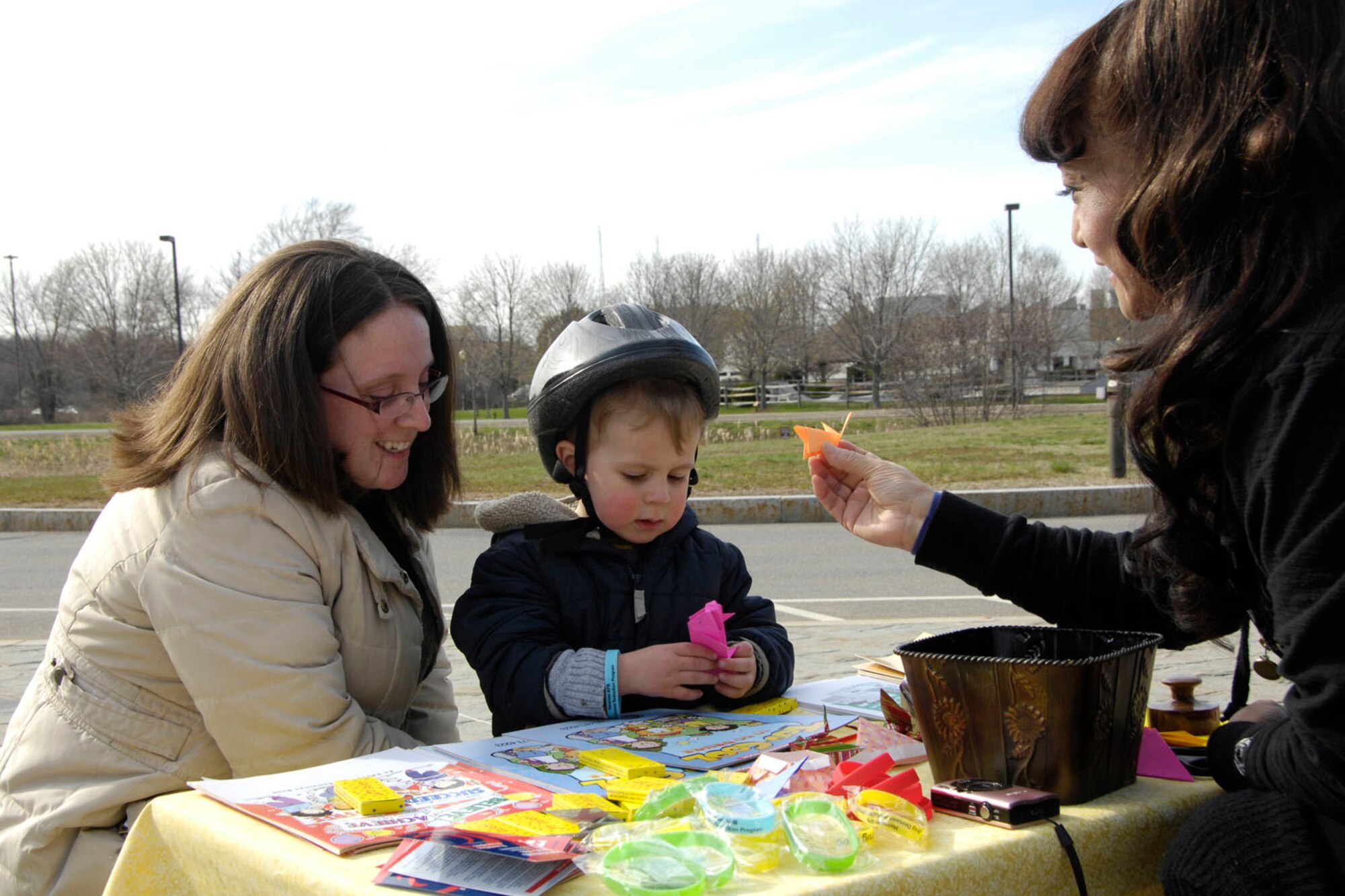HANSCOM AIR FORCE BASE, Mass. – June Howell (right) helps Kate and Aydin Ozpeynirci with origami during Family Appreciation Day at the Child Development Center April 22. The Family Advocacy Program, Base Chapel, CDC Parent Advisory Board, Equal Opportunity Office, Drug, Demand Reduction Program and Airman and Family Readiness Center provided parents with refreshments in the morning and played games with the kids and parents in the afternoon as part of Parents Appreciation Day and Child Abuse Awareness and Prevention Month. (U.S. Air Force photo by Linda LaBonte Britt)