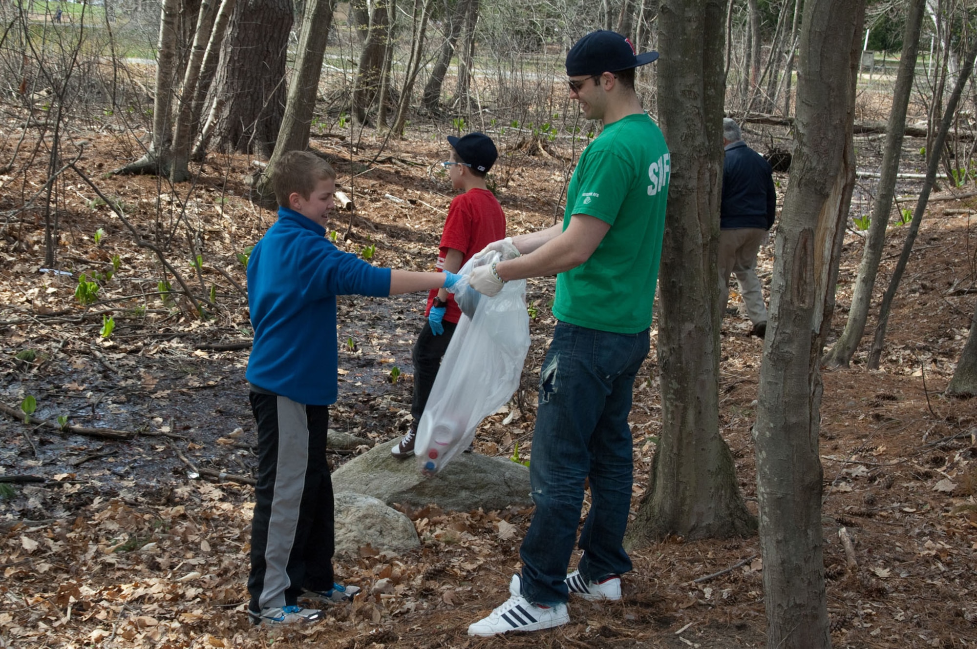 HANSCOM AIR FORCE BASE, Mass. – Trenton Sanders (left) throws a piece of trash in Christian Melitz’s trash bag during the Youth Center’s Earth Day Clean Cleanup April 22. Youth cleaned up the area around the Youth Center as part of an Earth Day project. (U.S. Air Force photo by Rick Berry)