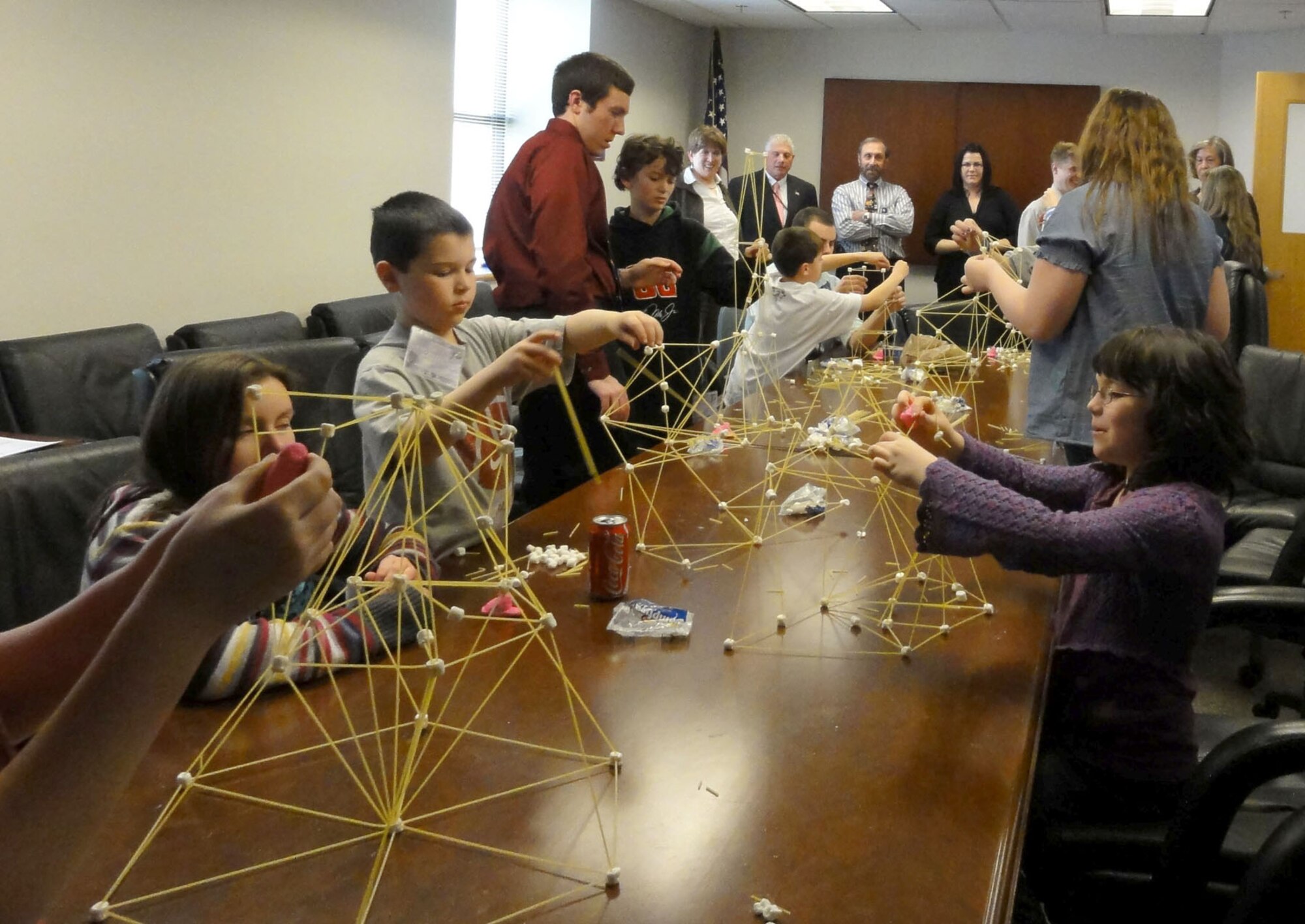 HANSCOM AIR FORCE BASE, Mass. – Children construct spaghetti towers during the “Bring Your Kid to Work Day” held by Capabilities Integration (XR) office last week. During the day, children of XR employees were invited to come to work with their parents. Engineer Yakov Salzberg explained to the kids why the Air Force uses antenna towers and why they need to be tall, load-bearing and strong. Then David LeBlanc, another engineer, gave the kids uncooked spaghetti and a mini marshmallows and instructed them to build a tall tower that could hold a Peep marshmallow somewhere on the structure. (Courtesy photo)