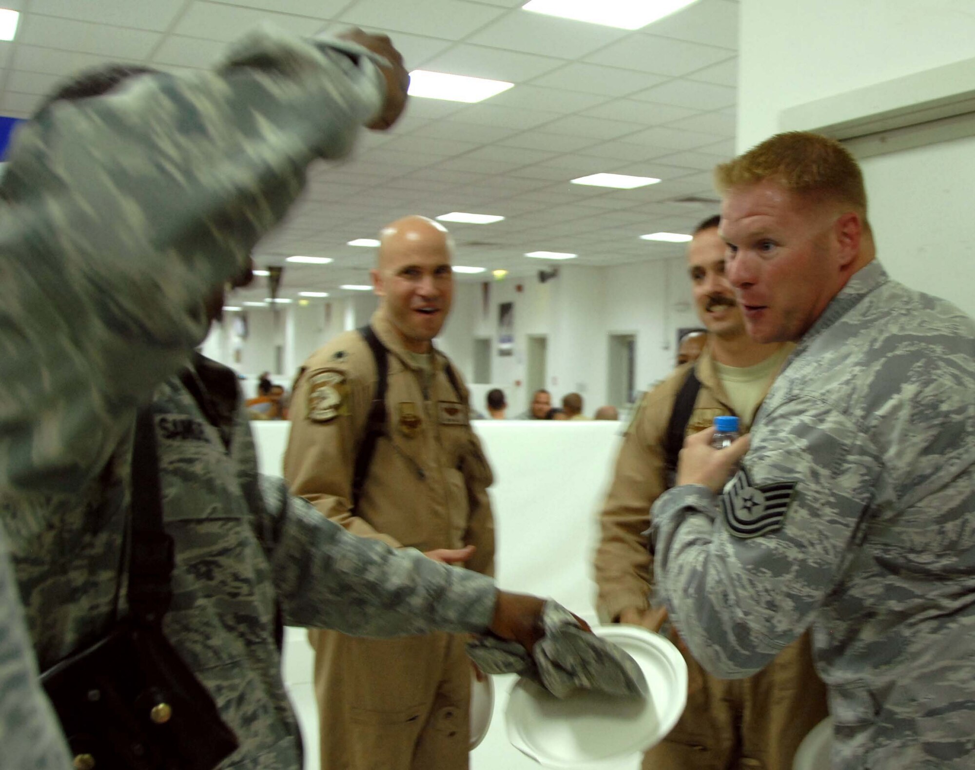 A coworker prepares to punch the rank onto the arm of newly promoted Tech. Sgt. Scott Richard, while other members of their 451st AEW Safety Office watch April 27, 2011 at Kandahar Airfield, Afghanistan. Tech. Sgt. Richard is the NCOIC of ground safety for the 451st AEW and was promoted during a visit by General Mark Welsh. (Photo by Tech. Sgt. Emily F. Alley)