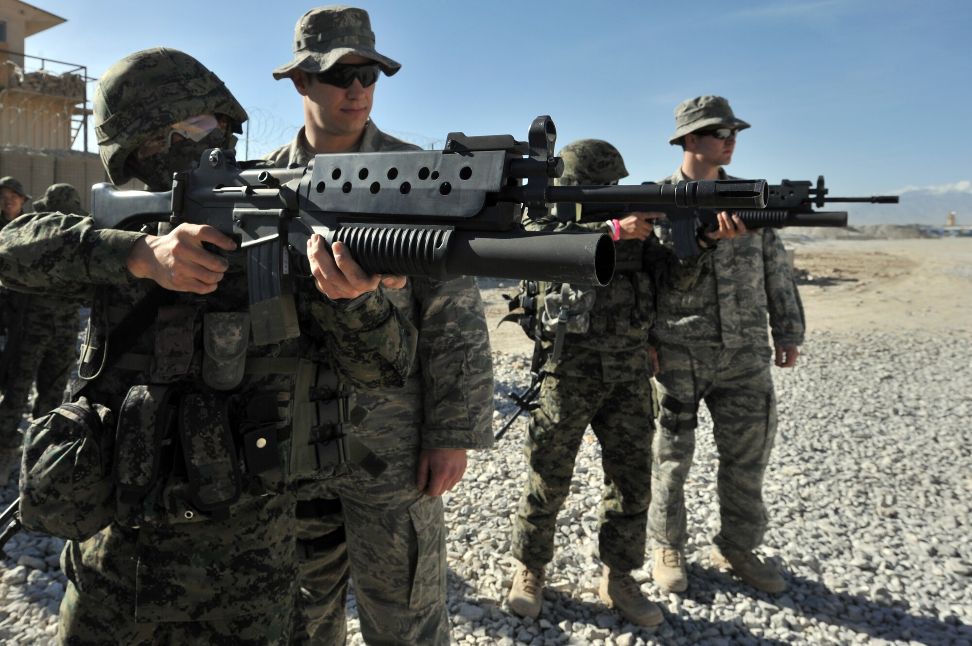 Senior Airman Gary Farmer (second from left) and Staff Sgt. Mason Flores, from the 455th Expeditionary Security Forces Squadron, watch Staff Sgt. Jon Myung Jae (left) and Staff Sgt. Kim Tae Young, Republic of Korea army security forces, fires a non-lethal 40mm sponge round during a M203 grenade launcher training at Bagram Airfield, Afghanistan, April 22, 2011. (U.S. Air Force photo by Senior Airman Sheila deVera)