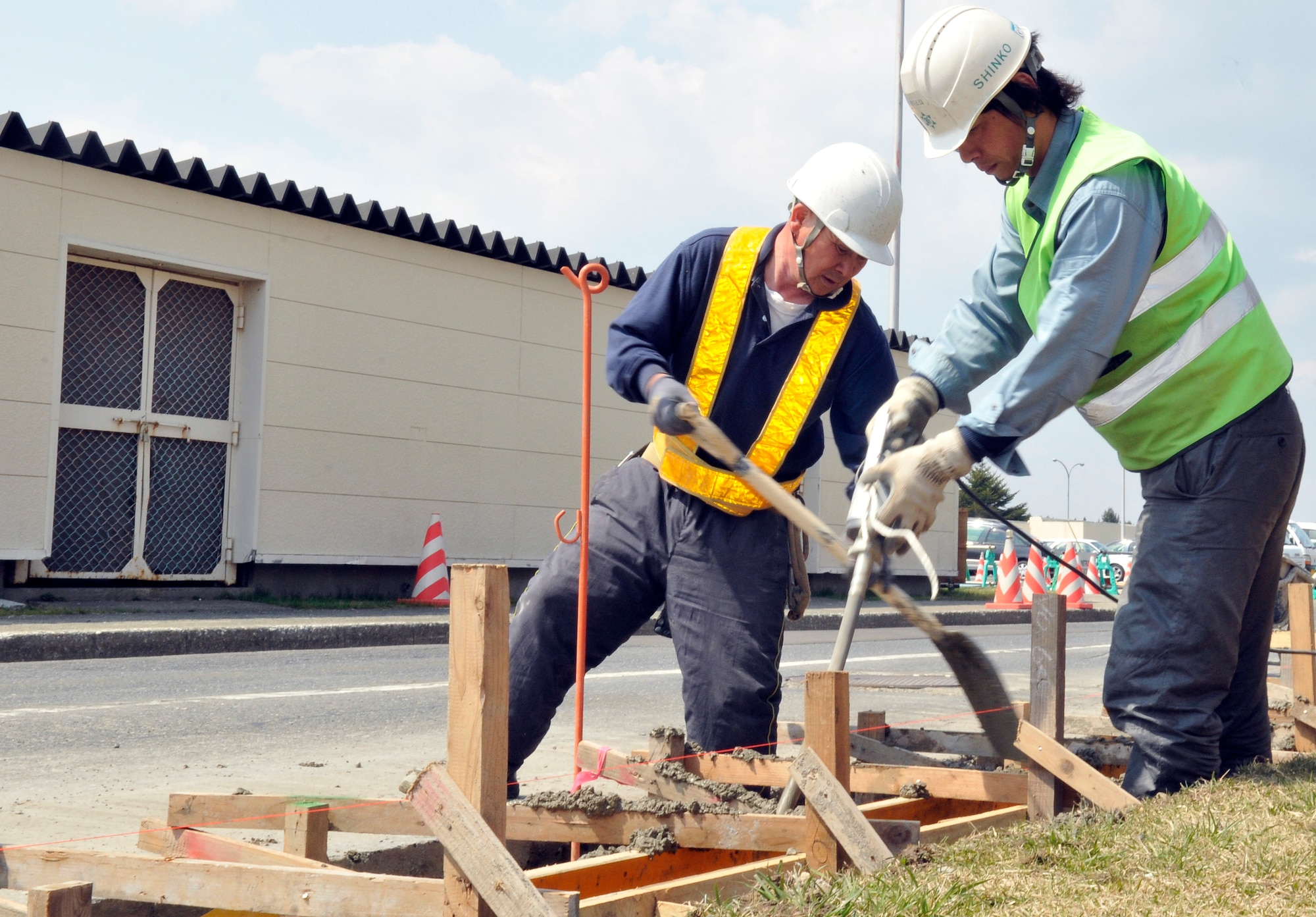 MISAWA AIR BASE, Japan – Shiraishi Koyou, left, and Saito Kengo, Japanese contractors, fill and level curbing forms on Fleming Street April 26. Forms are used to ensure the new curb will be straight and even after it dries. (U.S. Air Force photo/Tech. Sgt. Phillip Butterfield)