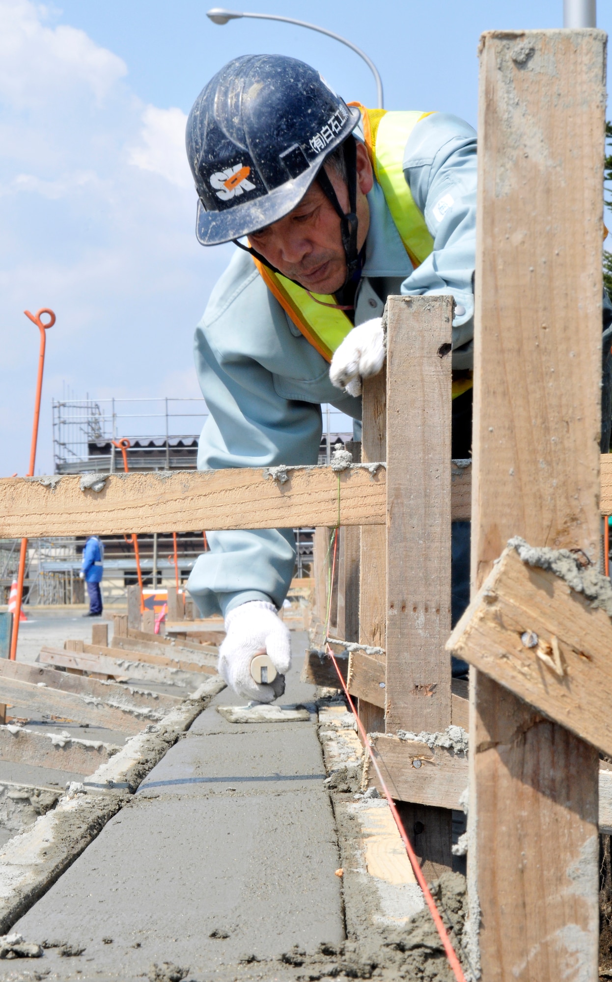 MISAWA AIR BASE, Japan – Ohshitanai Fumio, Japanese contractor, smoothes cement that has been poured into a curbing form on Fleming Street April 26. Cement-workers smooth for many reasons to include making the work more esthetic and more resilient to the effects of weather.  (U.S. Air Force photo/Tech. Sgt. Phillip Butterfield)