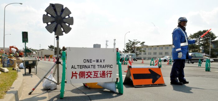 MISAWA AIR BASE, Japan – Segawa Hatsuhito, Misawa City guardsman, signals traffic to stop as a track hoe in the distance moves onto Fleming Street April 26. Contractors use guardsmen at most worksites where vehicles may come in contact with machinery. (U.S. Air Force photo/Tech. Sgt. Phillip Butterfield)