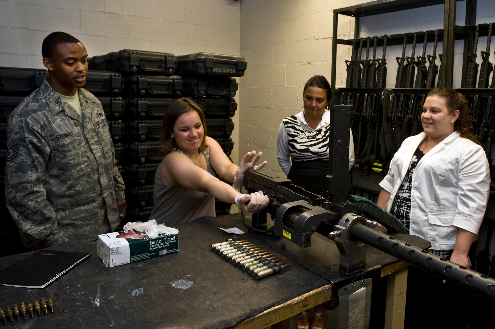 NELLIS AIR FORCE BASE, Nev. -- Tech. Sgt. Camden Stewart, 763rd Aircraft Maintenance Squadron, watches Heather Zehm,  use a 50. caliber machine gun at the 763rd Maintenance hanger during the quarterly Key Spouse event April 8.  Key Spouses is a base wide organization that allows spouses the opportunity to learn about different aspects of the Air Force while their husbands and wives are deployed. ( U.S Air Force Photo by Airman 1st Class Daniel Hughes)