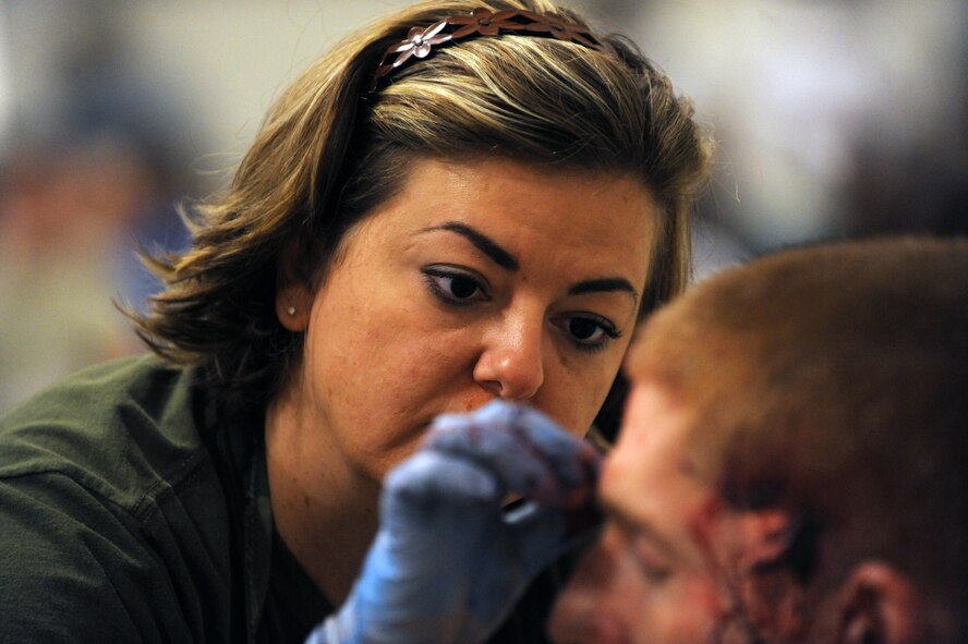 Staff Sergeant Christina Dickerson, 2nd Medical Group, applies make up and fake blood to a volunteer Airman in preparation for a Major Accident Response Exercise on Barksdale Air Force Base, La., April 29. Airmen who volunteered were assigned roles as injured bystanders, pilots and military personnel. Accident victims received a sheet listing their injuries, symptoms and emotional states to help them play their roles. (U.S. Air Force photo/Airman 1st Class Micaiah Anthony)(RELEASED)