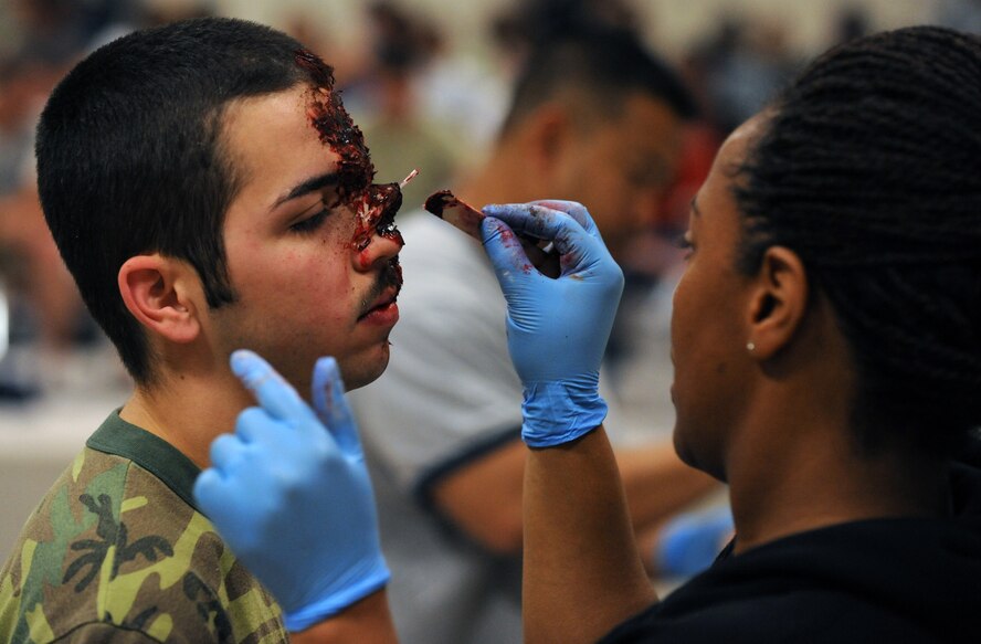 Tech. Sergeant Celia Lewis, 2nd Medical Group, applies fake blood and make up to Airman 1st Class Joshua Bibiloni, 2nd Maintenance Squadron, in preparation for a Major Accident Response Exercise on Barksdale Air Force Base, La., April 29. Airmen who volunteered were assigned roles as injured bystanders, pilots and military personnel. Accident victims received a sheet listing their injuries, symptoms and emotional states to help them play their roles. (U.S. Air Force photo/Airman 1st Class Micaiah Anthony)(RELEASED)