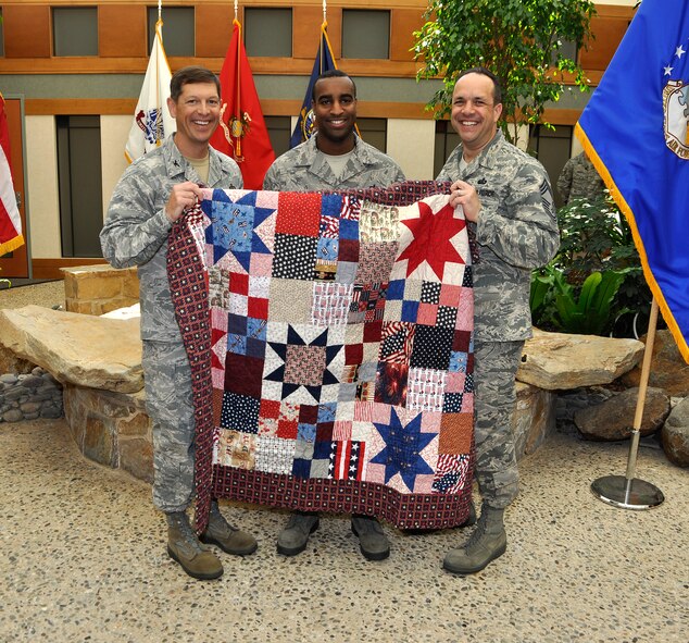 Col. Thomas C. Joyce, (left) Air Force Mortuary Affairs Operations commander and Chief Master Sgt. David Fish, (right) AFMAO enlisted manager, present Staff Sgt. Jeffrey Pughsley a Quilt of Valor for his work at the mortuary on behalf of a grateful American. Quilters from all over the nation make quilts for individuals affected by war. (U.S. Air Force photo/Tech. Sgt. Michael Stewart)