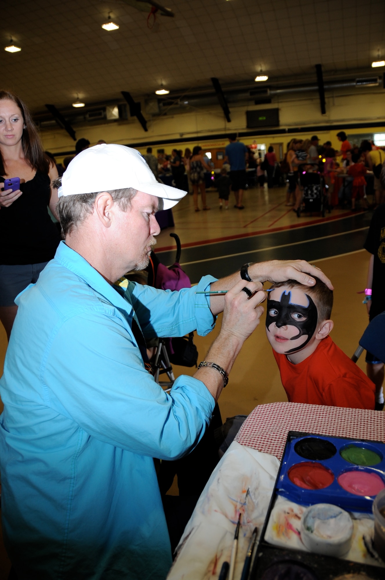 David Sipple applies the finishing touches on the Batman symbol to Landon Johnson, 5, during the Joint Base McGuire-Dix-Lakehurst Family Fun Fest at the Griffith Field House. More than 1,000 members of the community attended this years’ fun fest. (U.S. Air Force photo by Pascual Flores/Released)