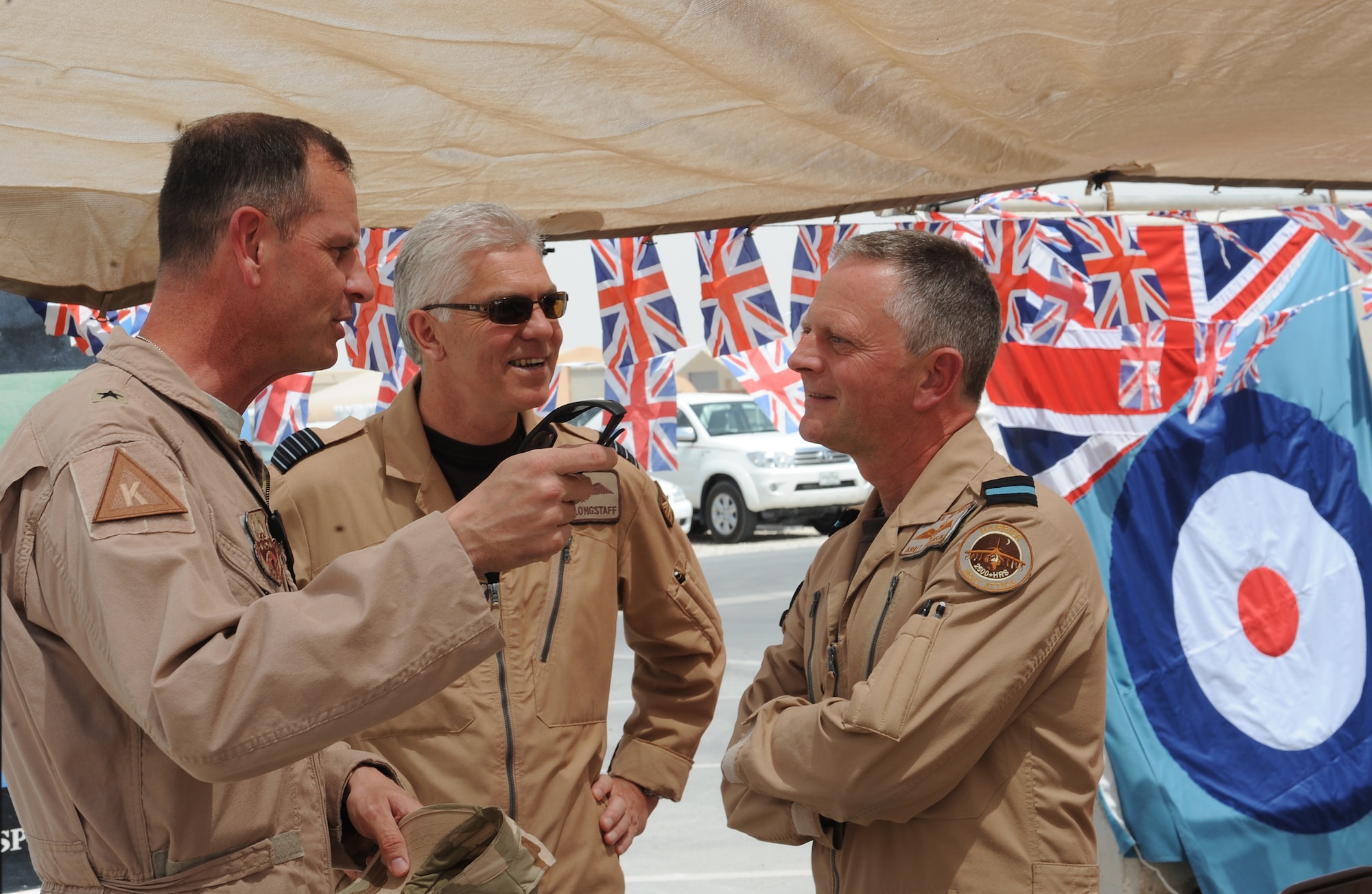 Brig. Gen. Randy Kee, 379th Air Expeditionary Wing commander, speaks with Group Captain Mike Longstaff, Deputy UK Air Component commander and Air Commodore Ashley Stevenson, UK Air Component commander, during the deployed members' street party celebration of the British Royal Wedding, April 29 in Southwest Asia. Street parties are a tradition which has been linked with royal and other national events for a century. (U.S. Air Force photo/Staff Sgt. Liliana Moreno)                                                       