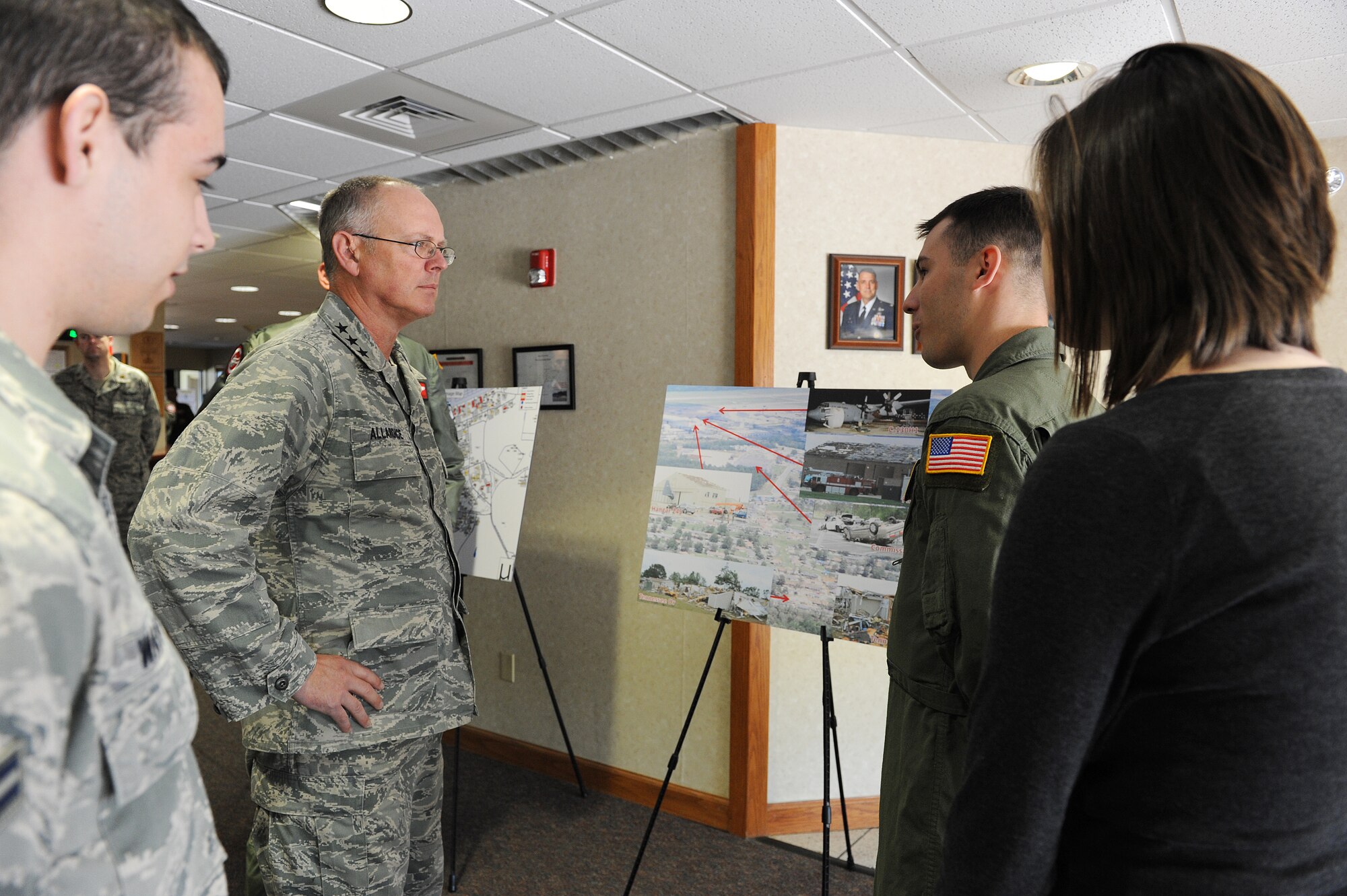 Senior Airman Eric McNair (second from right), a 19th Operations Support Squadron survival evasion resistance and escape specialist, and his wife, Alex, show photos of their damaged house to Lt. Gen. Robert Allardice, 18th Air Force commander, on April 28, 2011, at Little Rock Air Force Base, Ark.  The couple described how they survived when a tornado struck the base April 25 and caused their house to collapse around them. (U. S. Air Force photo by Airman 1st Class Ellora Stewart)