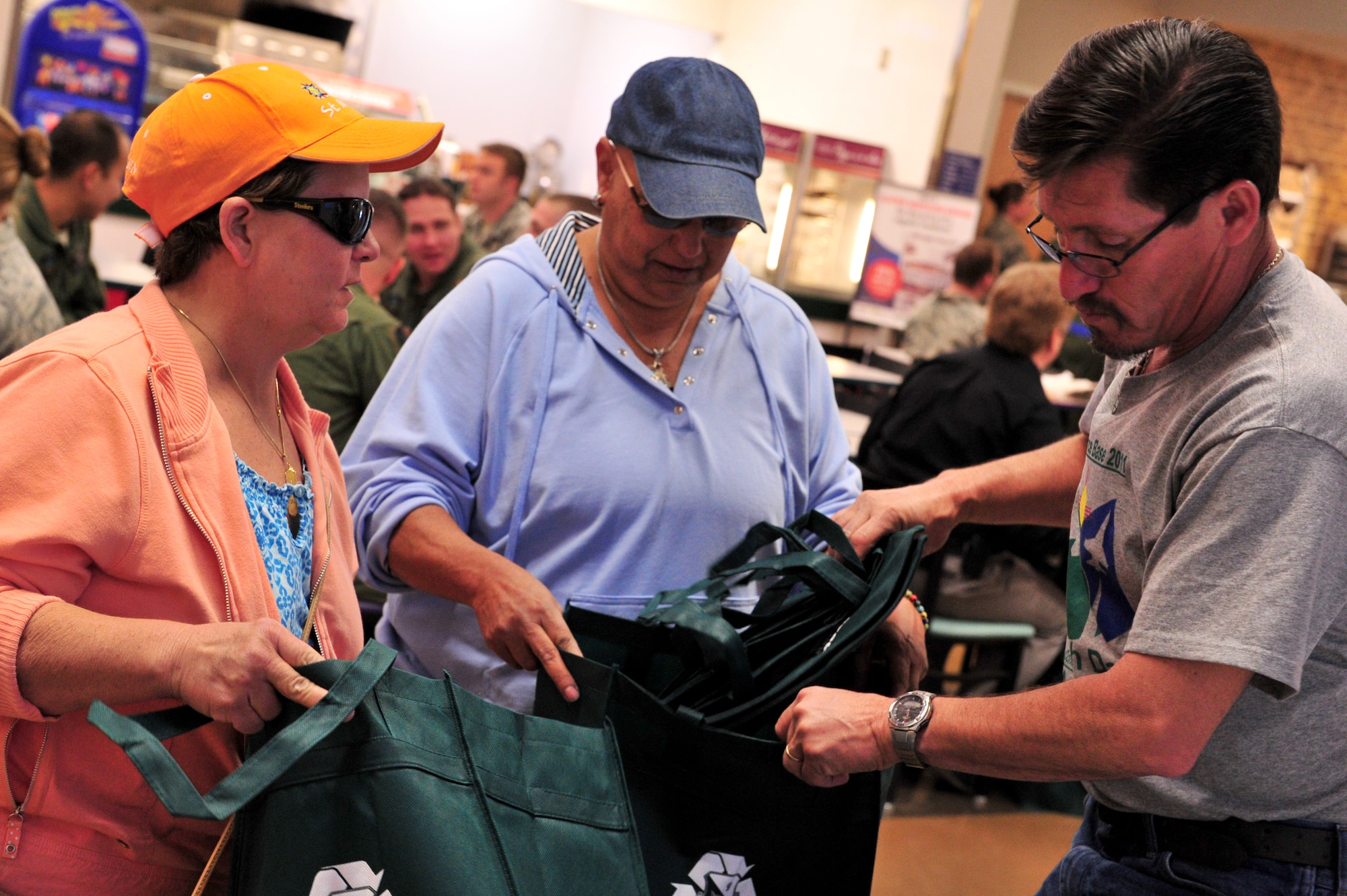 Mr. Jake Madril, 27th Special Operations Civil Engineer Squadron, gives recyclable bags to two Base Exchange and Commissary patrons April 28, 2011. The Asset Management Flight of the 27th Special Operations Civil Engineer Squadron handed out information, reusable cups and souvenirs in support of Earth Day and Arbor Day.  (U.S. Air Force photo by Tech. Sgt. Josef Cole)(RELEASED)