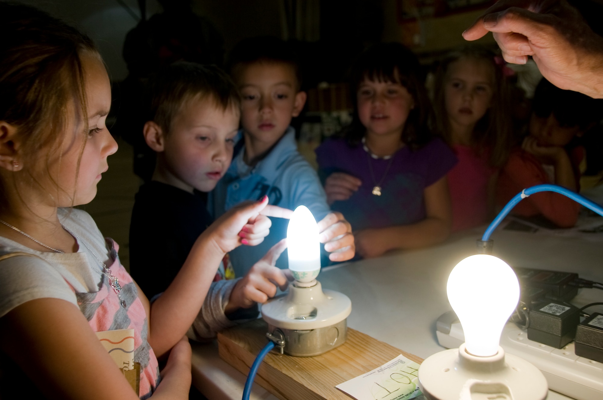 From left, Hailee Esquibel, William Maness and Holland McCord feel a compact fluorescent light bulb April 20 during an Earth Day event at the Youth Center.  U.S. Air Force Photo by Elizabeth Martinez
