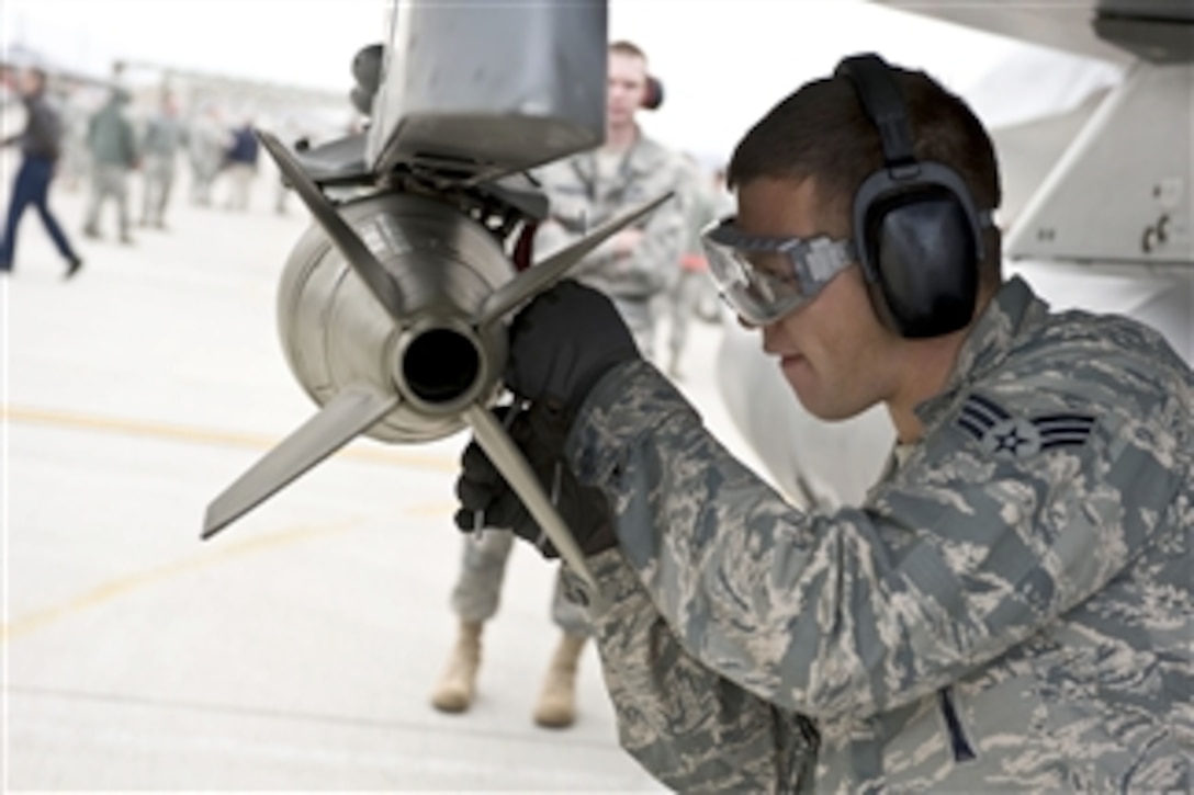 Senior Airman Lucas Wolf loads a bomb onto an F-16 Fighting Falcon at Nellis Air Force Base, Nev., during a quarterly weapons load competition on April 8, 2011.  Wolf is a load-crew member assigned to the 57th Aircraft Maintenance Squadron.  