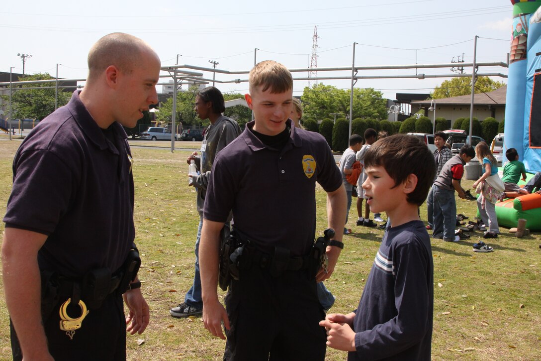 Alex Knueppel, a Matthew C. Perry Elementary School fourth-grader, asks Lance Cpl.'s Daniel J. Schumi and Christopher Korsikas, both station military policemen, what it is like to be a police officer during the Month of the Military Child picnic held at the M.C Perry soccer fields here April 29. The picnic was held to bring the MOnth of the Military Child to a close.