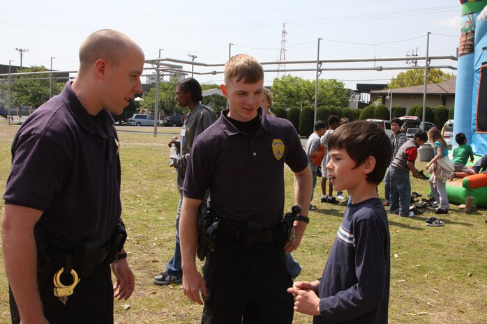 Alex Knueppel, a Matthew C. Perry Elementary School fourth-grader, asks Lance Cpl.'s Daniel J. Schumi and Christopher Korsikas, both station military policemen, what it is like to be a police officer during the Month of the Military Child picnic held at the M.C Perry soccer fields here April 29. The picnic was held to bring the MOnth of the Military Child to a close.