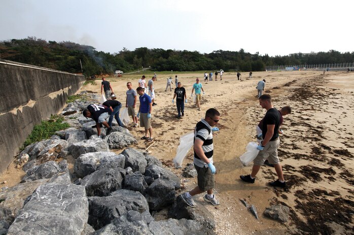 Marines don plastic gloves and fill trash bags full of debris during a beach cleanup at Kin Red beach Aug. 13, 2011. Countless bags of trash and other debris were collected during the cleanup effort.