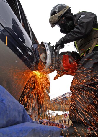 Bloomington, Minn., native, Marine Corps Sgt. Nicholas Janey, a technical rescueman with the Chemical, Biological Incident Response Force, demonstrates how he would use a saw to force his way into a vehicle to extract a person during a chemical, biological or nuclear event at Yokota Air Base, Japan, April 23. The Marines of CBIRF and the Japan Ground Self Defense Forces demonstrated their collective ability to work together in a chemical, biological or nuclear event to Japan's Minister of Defense Toshimi Kitazawa and Air Force Lt. Gen. Burton M. Field, commander of the Joint Support Force and the United States Forces, Japan.::r::::n::::r::::n::::r::::n::