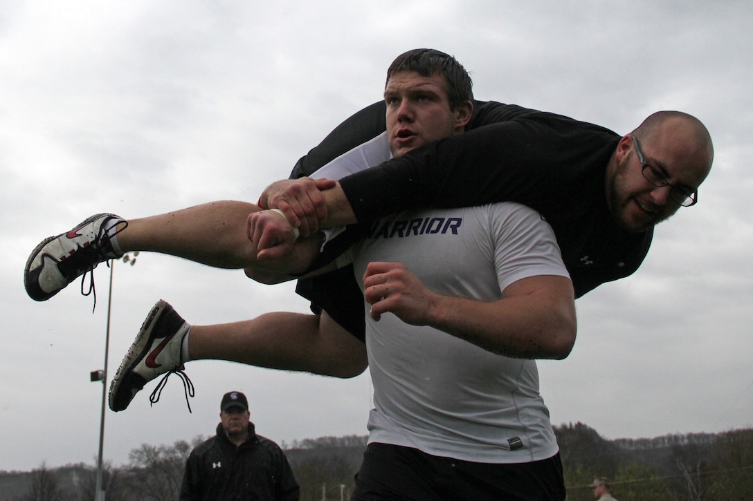 Tom Sawyer, head coach for the Winona State Warriors, watches Jacob Harmon carry fellow linebacker Alex Kautza during the maneuver under fire portion of a modified combat fitness test at Maxwell Field April 30. Harmon, from Dodge Center, Minn., and Kautza, from Antigo, Wis., are both seniors at Winona State University. More than 40 members of the football participated in the event. For more photos of the event, visit www.facebook.com/rstwincities.