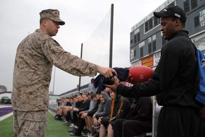 Staff Sgt. Jackie F. Culbertson, 33, from Griffin, Ga., hands Winona State Warrior Anthony Resnick, a running back and redshirt freshman, some Marine Corps memorabilia for completing the maneuver under fire portion of a modified combat fitness test at Maxwell Field April 30 with the fastest time. Resnick, a Cambridge, Wis., native, completed the event in 1:31. Culbertson is the Recruiting Substation Rochester noncommissioned officer in charge. For more photos of the event, visit www.facebook.com/rstwincities.