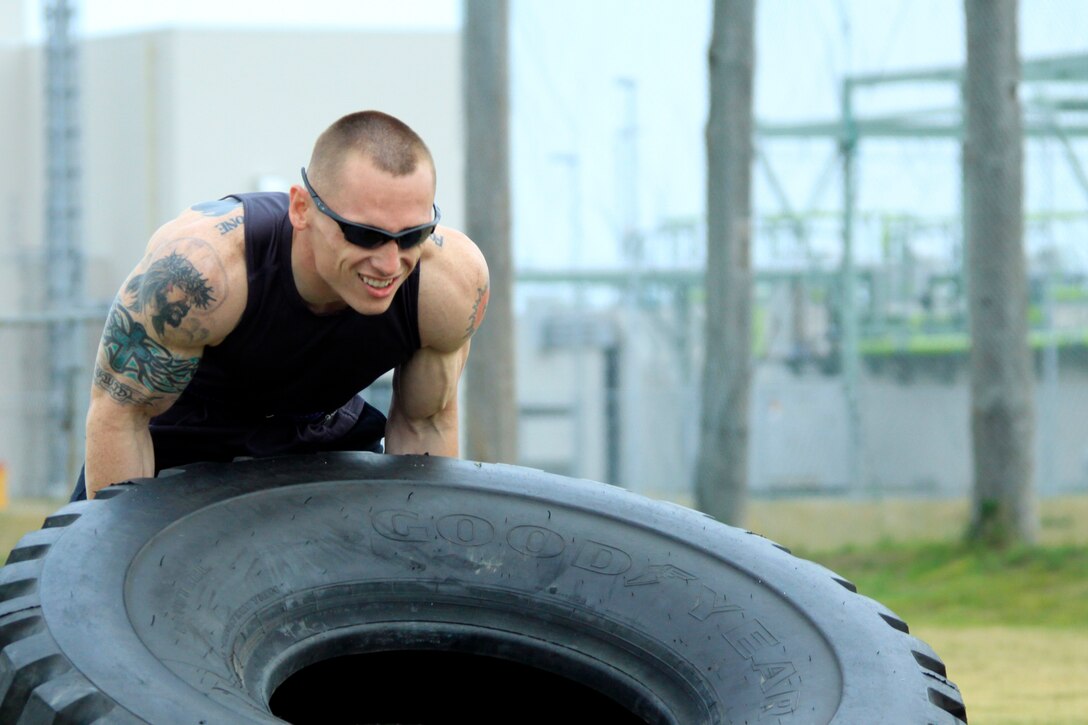 Chris Junkins, 160-and-under pound men's weight group division competitor, performs a tire flip during the annual Iwakuni Strongman Competition at the Penny Lake field here April 30. Junkins carried 250 pounds during the farmer's walk across 100 meeters, 30 7-ton tire flips, 31.03 seconds during the iron cross, 35 reps during teh steel log press, and 25 seconds durng the Humvee pull.