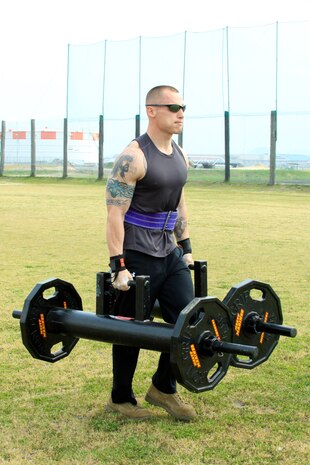 Chris Junkins, 160-and-under pound men's weight group division competitor, carries 250 pounds of weight during the annual Iwakuni Strongman Competition at the Penny Lake field here April 30. Junkins carried 250 pounds during the farmer's walk across 100 meeters, 30 7-ton tire flips, 31.03 seconds during the iron cross, 35 reps during teh steel log press, and 25 seconds durng the Humvee pull.