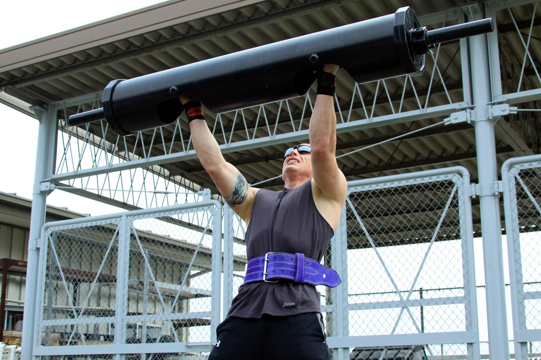 Chris Junkins, 160-and-under pound men's weight group division competitor, pushes out a steel log press repetition during the annual Iwakuni Strongman Competition at the Penny Lake field here April 30. Junkins carried 250 pounds during the farmer's walk across 100 meeters, 30 7-ton tire flips, 31.03 seconds during the iron cross, 35 reps during the steel log press, and 25 seconds durng the Humvee pull.
