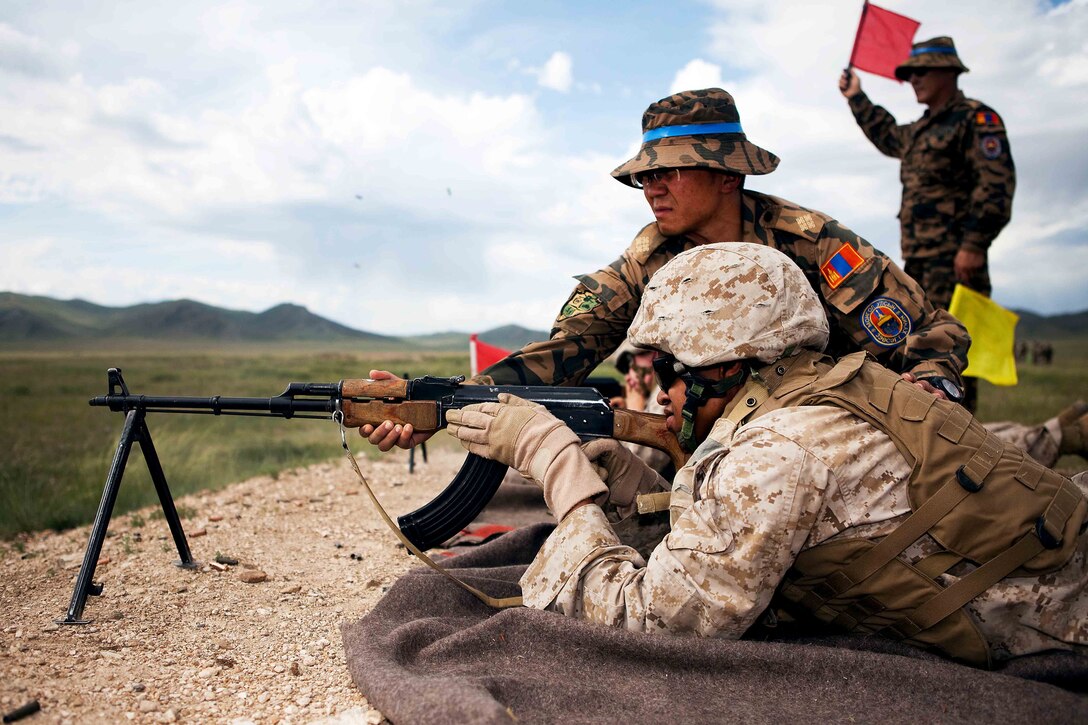 Capt. Altanzorig Zorigt, head trainer, Unit 311, Peace Support Operations Training Center, Mongolian armed forces, assists a Marine with an AK-47 automatic rifle during the live fire portion of the field training exercise at Exercise Khaan Quest 2011 at Five Hills Training Area near Ulaanbaatar, Mongolia, Aug. 1. Khaan Quest is a training exercise designed to strengthen the capabilities of U.S., Mongolian and other participating nations’ forces in international peace support operations worldwide.