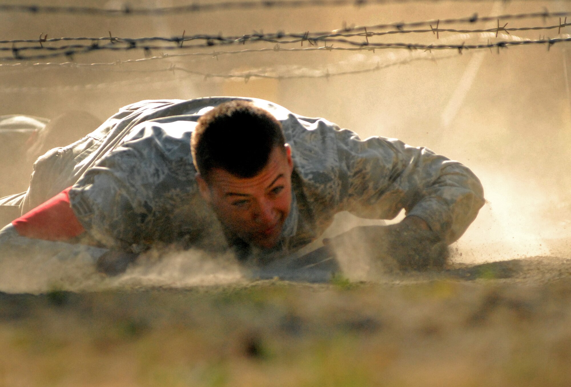 Senior Airman Jeffrey Kristek, 647th Security Forces Squadron, low-crawls under barbed wire during the 2011 Air Mobility Rodeo at Joint Base Lewis-McChord, Wash., July 28. Kristek is stationed at Joint Base Pearl Harbor-Hickam, Hawaii. (U.S. Air Force photo by Staff Sgt. Carolyn Herrick)