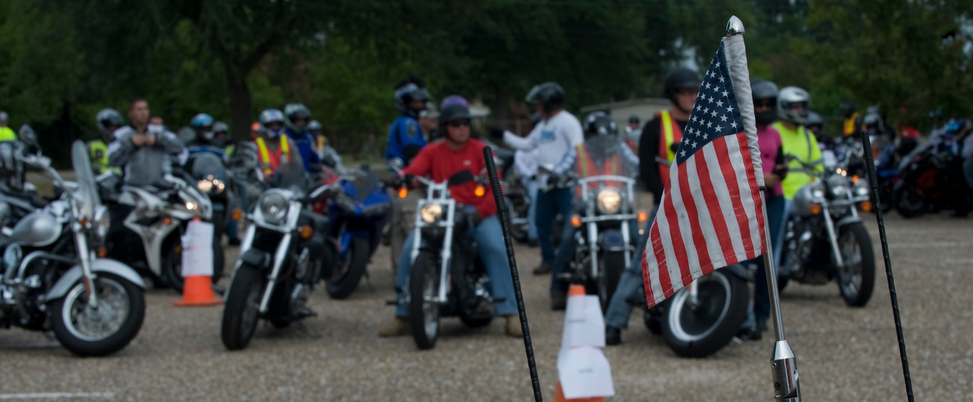 An American flag sits on the back of a motorcycle as participants start their bikes and don their protective gear before the Motorcycle Awareness and Remembrance Ride on Barksdale Air Force Base, La., July 29. In order to operate a motorcycle on Barksdale, a rider must have a valid state motorcycle license, Motorcycle Safety Foundation training card, proof of insurance, registration and the required personal protective equipment. (U.S.  Air Force photo/Airman 1st Class Micaiah Anthony)(RELEASED)