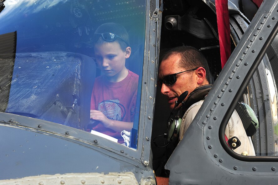 U.S. Air Force Tech. Sgt. Kenneth Clark, 71st Rescue Squadron crew chief loader technician, teaches his son Korey about the different components of the HH-60G Pave Hawk as he sits in the pilot’s seat at Moody Air Force Base, Ga., July 28, 2011. The kids attending Bring Your Child to Work Day were excited to be able to sit in the pilot and aerial gunner seats of the HH-60 Pave Hawk. (U.S. Air Force photo by Senior Airman Stephanie Mancha/Released)