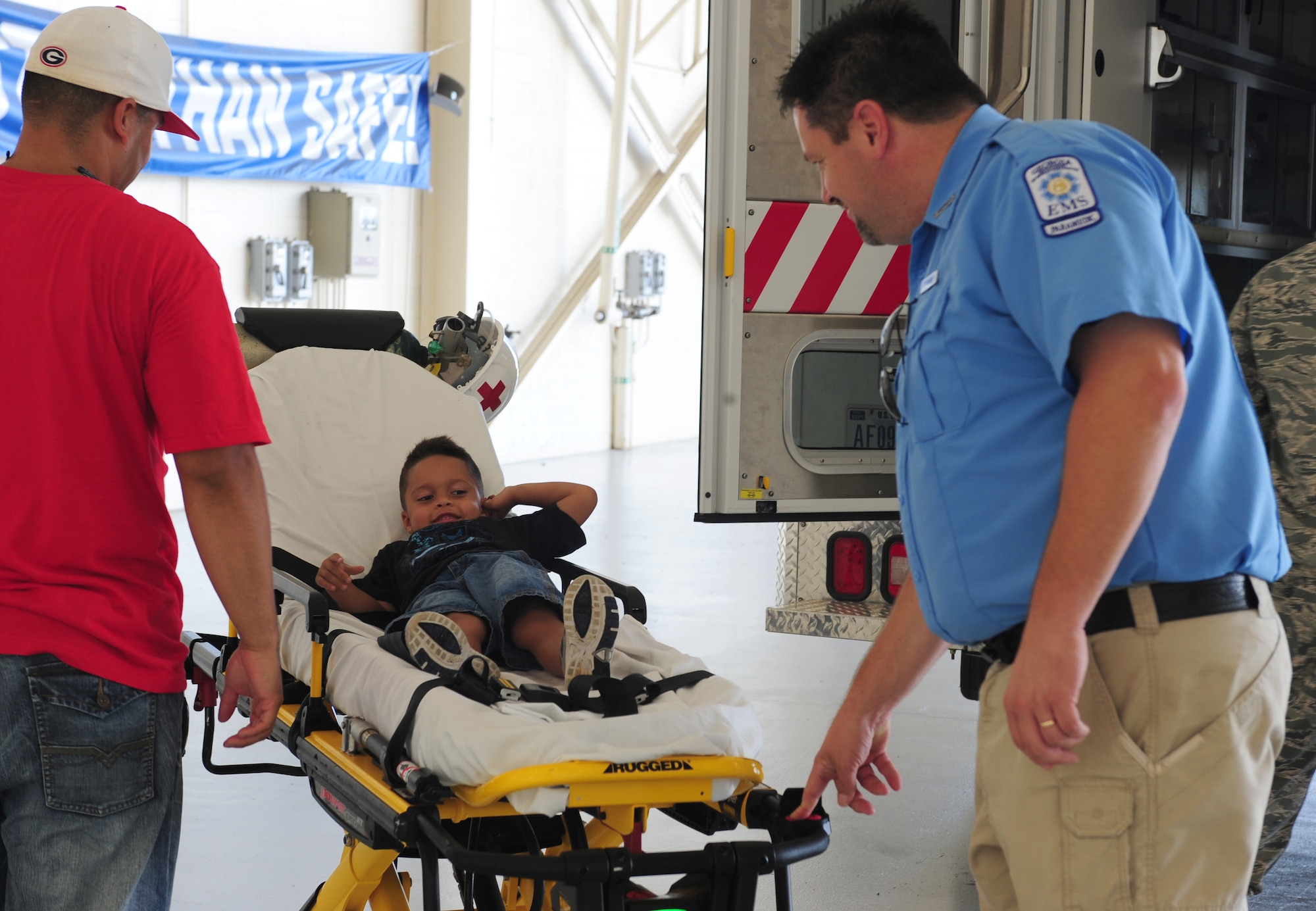 Anthony, son of U.S. Air Force Staff Sgt. Jose Gonzalez, 23rd Civil Engineer Squadron heating, ventilation, and air conditioning technician, lays on a striker power stretcher as James Brower, 23rd Aerospace Medicine Squadron ambulance dispatcher, raises and lowers the stretcher at Moody Air Force Base, Ga., July 28, 2011. During Bring Your Child to Work Day the children were giving the opportunity to see static displays of emergency vehicles and aircraft. (U.S. Air Force photo by Senior Airman Stephanie Mancha/Released)
