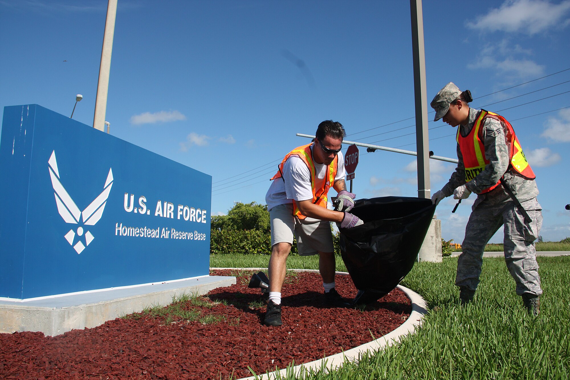 Senior Airman Patricia Trimble, 482d Fighter Wing Honor Guard works with a Job Corps Joint Uniform Military Prep student to assist in a community road-side clean up on July 28. Thirty two people from Job Corps and Homestead Air Reserve Base paired up to pick up trash along 288th Street, starting at 137th Avenue to the Job Corps center. (U.S. Air Force photo by Senior Airman Lou Burton, 482nd Fighter Wing Public Affairs)