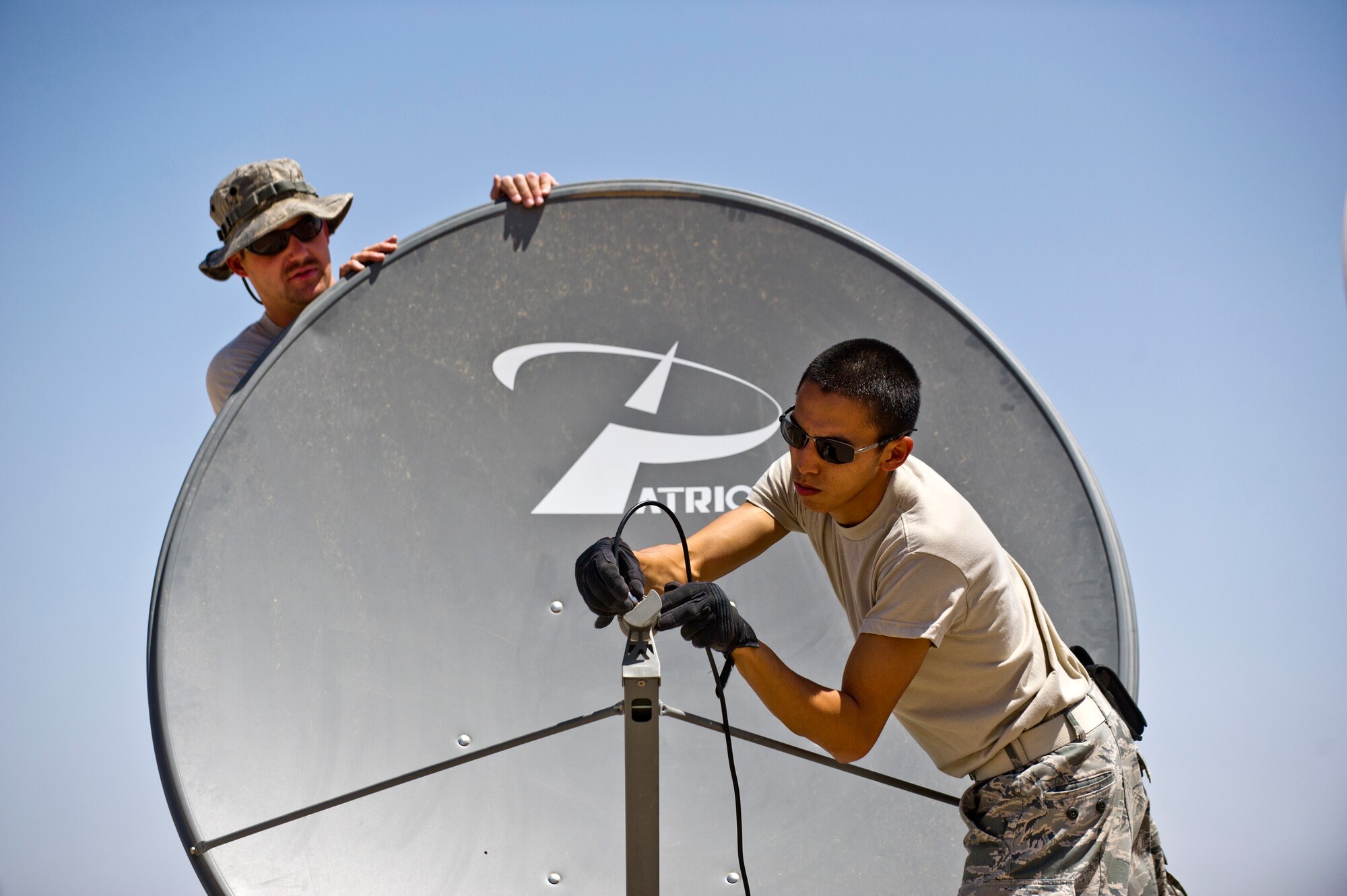 Staff Sgt. Andrew Lewis (left) and Senior Airman Jose Cortez, Detachment 1, 73rd Expeditionary Air Control Squadron, install a satellite dish at Camp Etchberger. Once installed, the new dish will allow the televisions in the camp to connect to the armed forces network. (U.S. Air Force Photo/Master Sgt. Jeffrey Allen)